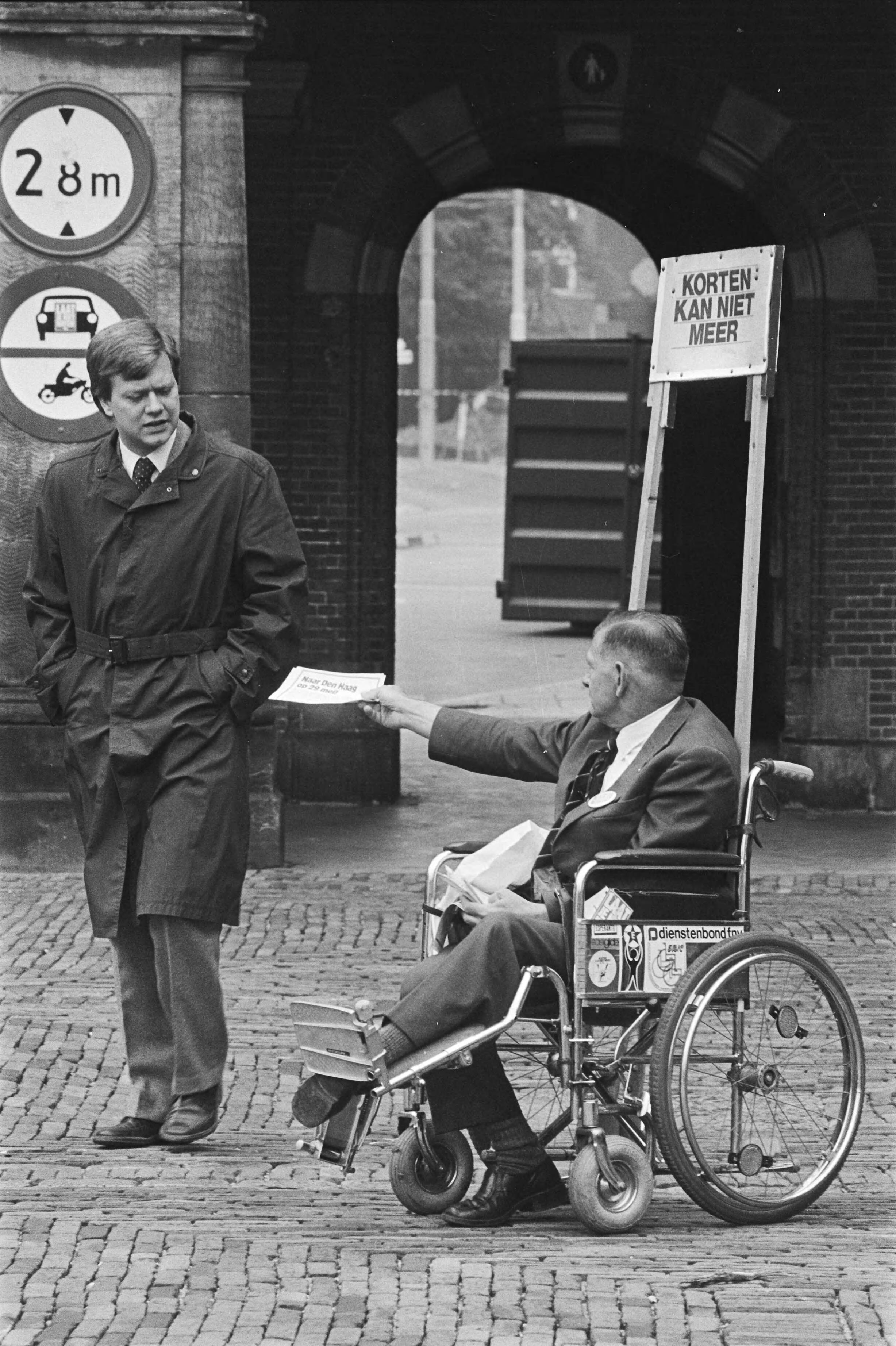 Fotocollectie Anefo — Acties tegen de 1 juli-maatregelen op Binnenhof Den Haag actievoerende WAO-er (in rolstoel) deelt pamfletten uit — Foto: Croes, Rob C. / Anefo. Licentie: Set B: Rechtenvrij / Publiek Domein. Bron: Nationaal Archief. http://hdl.handle.net/10648/ad391fa6-d0b4-102d-bcf8-003048976d84