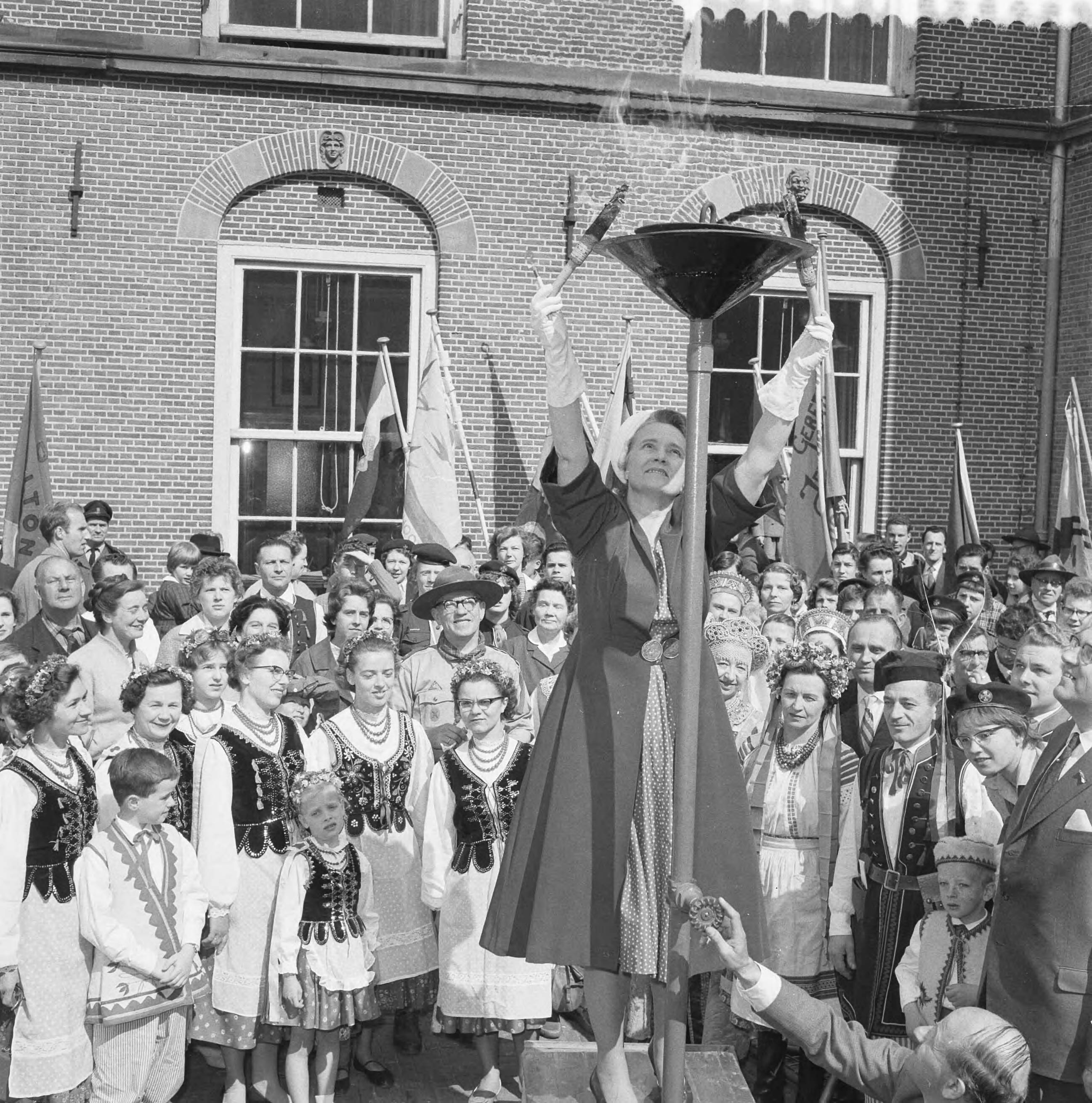 Fotocollectie Anefo — Ontsteken van het bevrijdingsvuur door minister Klompé op het Binnenhof te Den Haag — Foto: Behrens, Herbert F. / Anefo. Licentie: Set B: Rechtenvrij / Publiek Domein. Bron: Nationaal Archief. http://hdl.handle.net/10648/a9adf9f6-d0b4-102d-bcf8-003048976d84