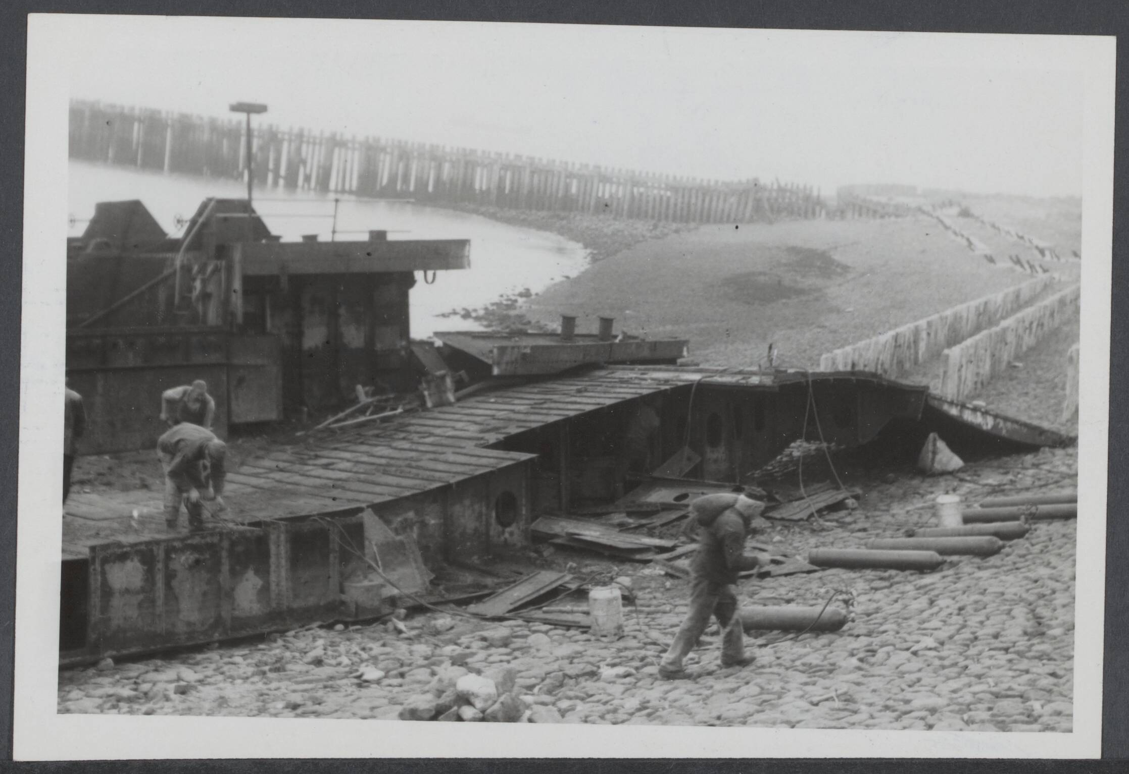 Slechten vestingwerken, vernietiging en vinden oorlogsmateriaal, demilitarisering, opslag, dumps. Nederland. — De dijk van Westkapelle werd in oktober 1944 door Britse vliegtuigen en scheepsartillerie kapot geschoten teneinde de bevrijding van Nederlandd te bespoedigen. De landingsvaartuigen liggen nog steeds op de dijk van Westkapelle en worden met behulp van snijbranders gesloopt om de laatste sporen van deze periode uit te wissen — Foto: Merk, Ben / Anefo. Licentie: Set B: Rechtenvrij / Publiek Domein. Bron: Nationaal Archief. http://hdl.handle.net/10648/8b646ac1-0a20-a9f7-1dfd-3c8f64ac4a2b