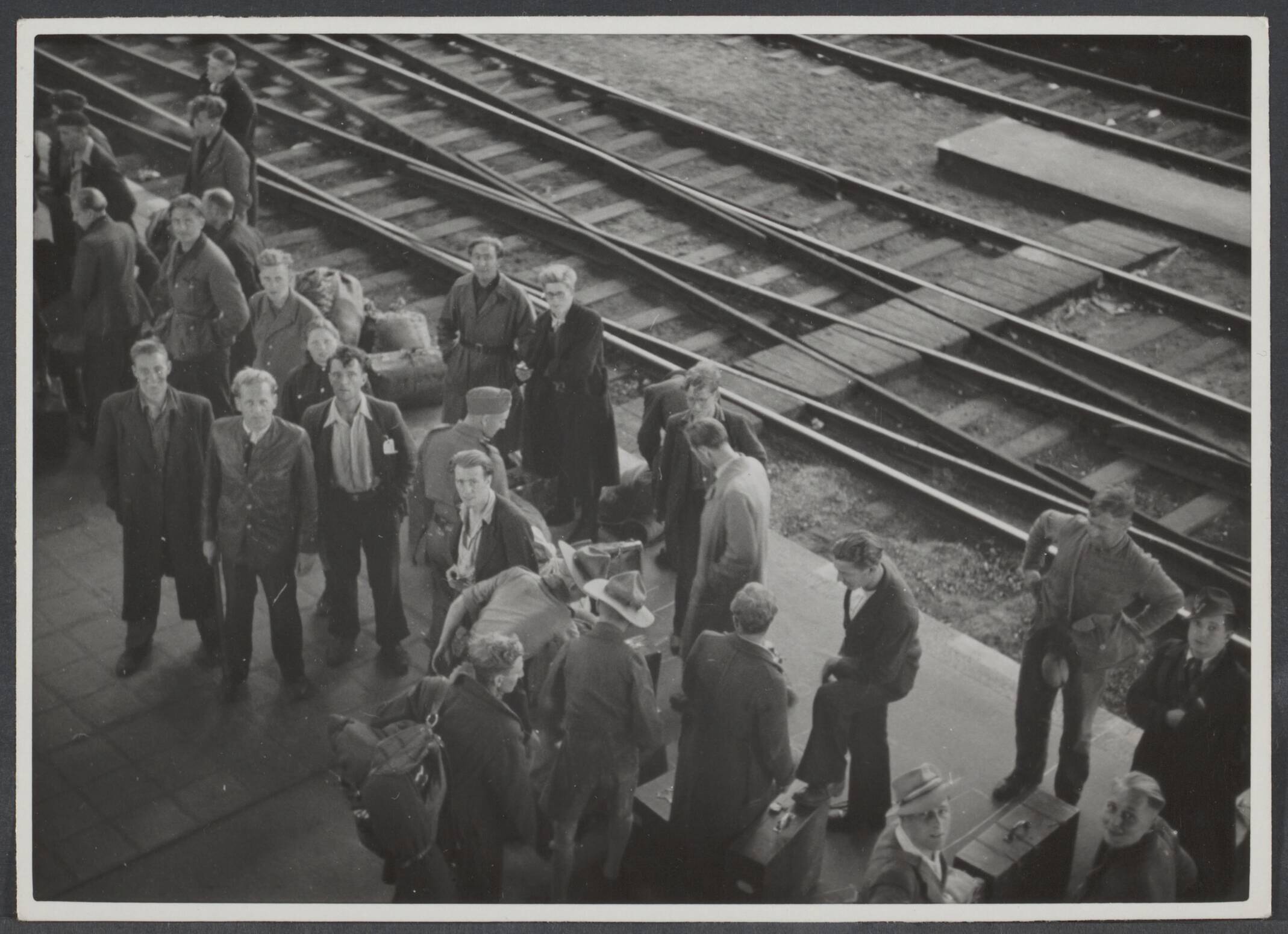 Arbeidsdienst. Waaronder "Nederlandse Arbeidsdienst" en "Vreugde en Arbeid" ("Fut door lol" 81). Ook opbouwdienst 1940/41. — [Serie: repatriëring Arbeitseinsatz] Juni-Juli 1945. Terug in Nederland. Station Haarlem. Nederlandse gedeporteerden behouden teruggekeerd in de stad van hun inwoning — Foto: Bosen, Frans / Spaarnestad. Licentie: Set B: Rechtenvrij / Publiek Domein. Bron: Nationaal Archief. http://hdl.handle.net/10648/87d7ceb4-4e50-63a4-cd60-60672bdd19e3