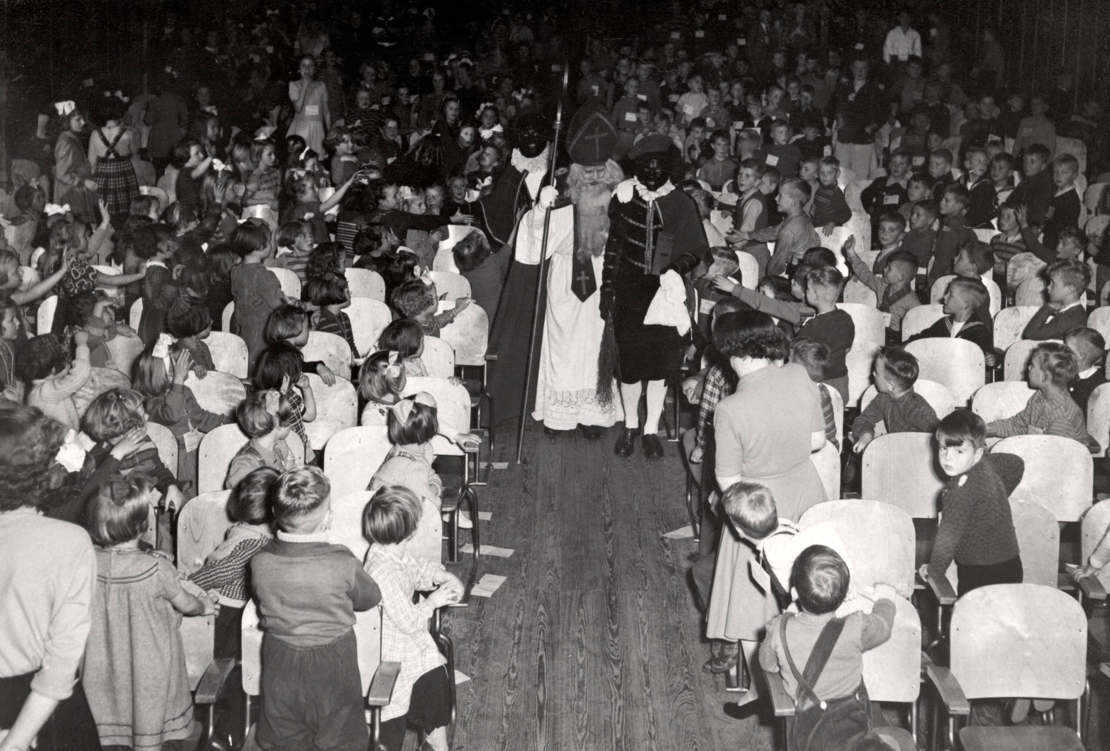 Collectie nader te bepalen — [Sinterklaasfeest N.V. Drukkerij De Spaarnestad in Haarlem] [binnenkomst van Sinterklaas en Zwarte Pieten] — Foto: Fotograaf Onbekend / Fotobureau onbekend / Spaarnestad Photo (05887). Licentie: Set B: Rechtenvrij / Publiek Domein. Bron: Nationaal Archief. http://hdl.handle.net/10648/35429da6-4063-a382-e063-6df0900a6686