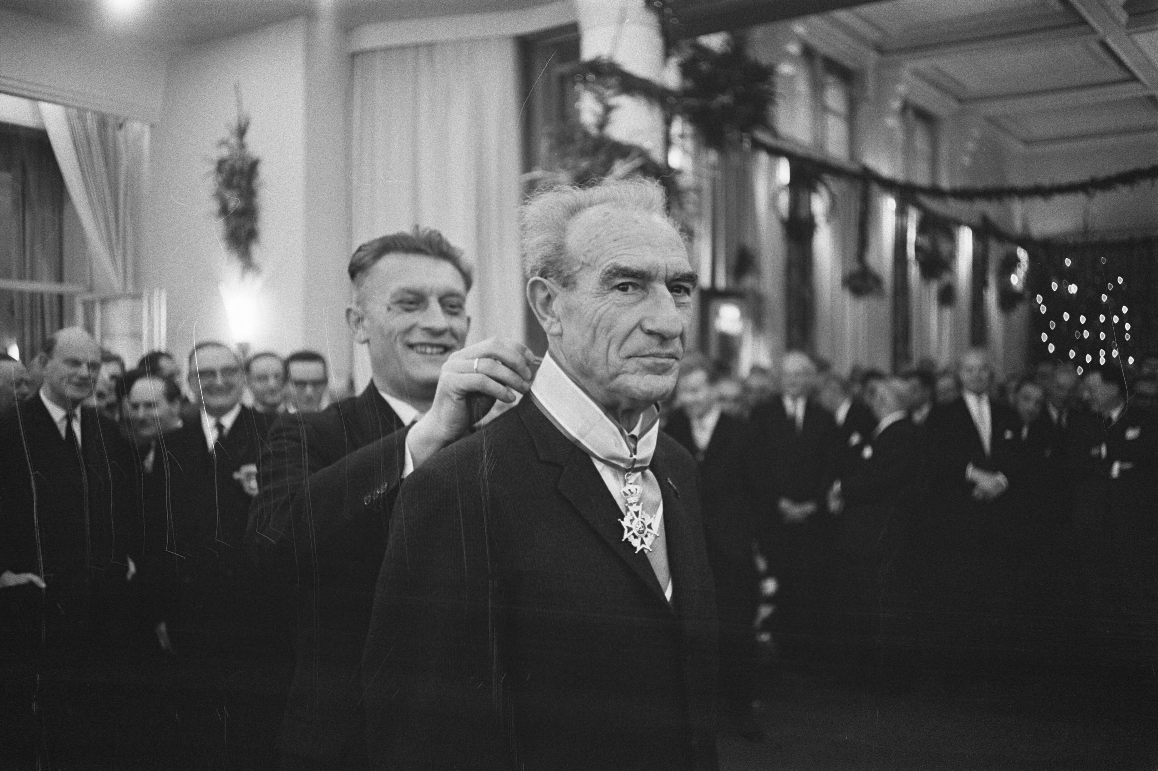 Fotocollectie Anefo — Afscheidsreceptie van de voorzitter van het College van Rijksbemiddelaars mr. J.A. Berger, staatssecretaris Roolvink hangt hem versierselen van de koninklijke onderscheiding tot commandeur in de Orde van Oranje Nassau om — Foto: Pot, Harry / Anefo. Licentie: Set B: Rechtenvrij / Publiek Domein. Bron: Nationaal Archief. http://hdl.handle.net/10648/a9c3f706-d0b4-102d-bcf8-003048976d84