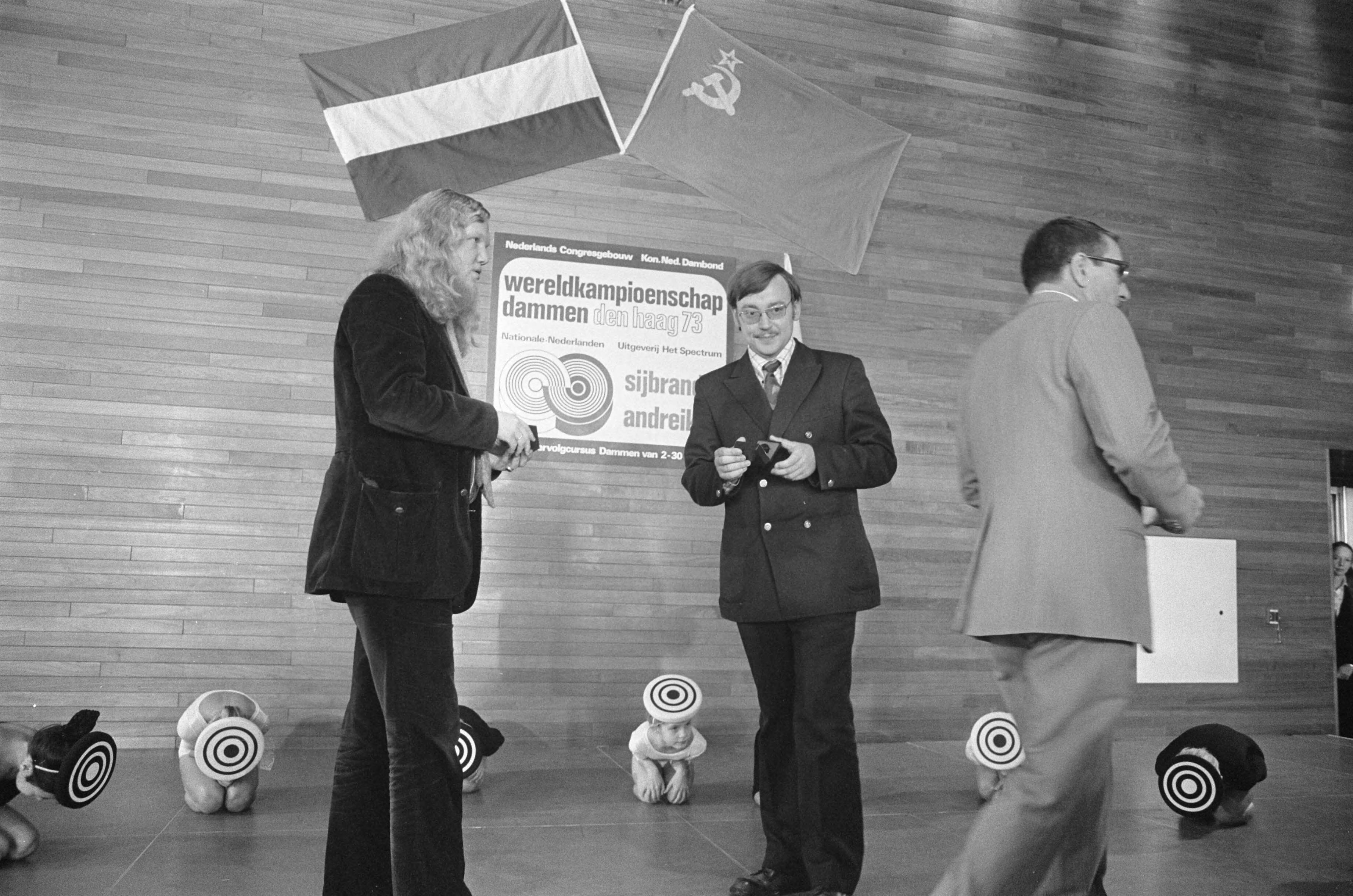 Fotocollectie Anefo — Sijbrands (links) en Andreiko loten voor wereldkampioenschappen dammen in Den Haag — Foto: Verhoeff, Bert / Anefo. Licentie: Set B: Rechtenvrij / Publiek Domein. Bron: Nationaal Archief. http://hdl.handle.net/10648/ac382ffc-d0b4-102d-bcf8-003048976d84