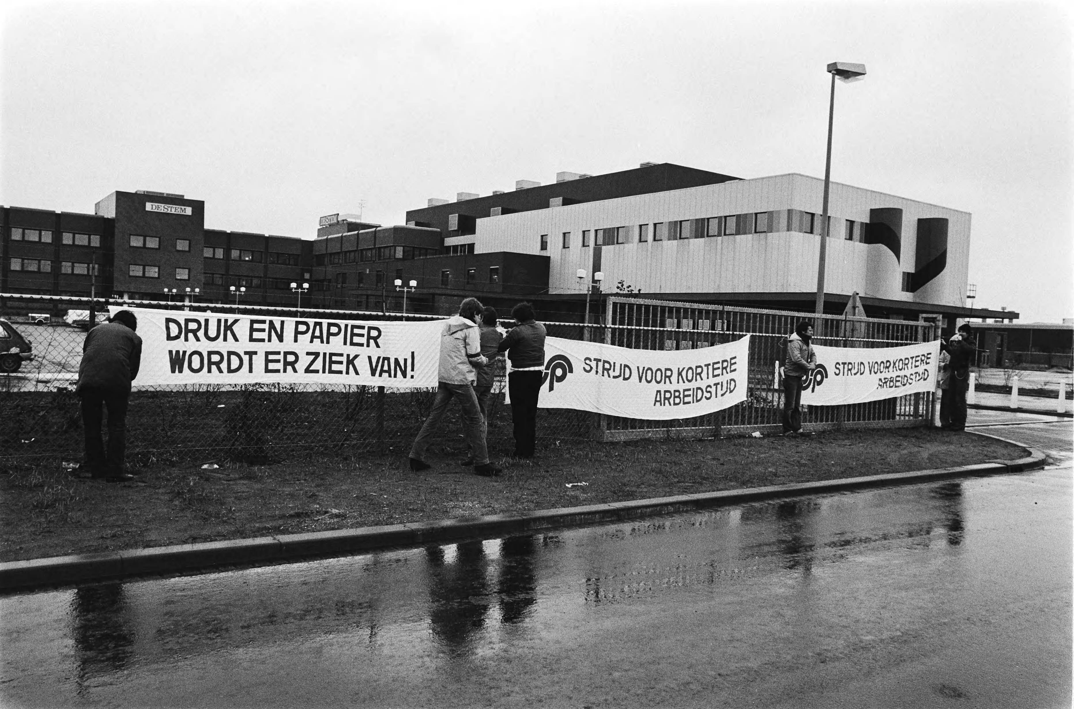 Fotocollectie Anefo — Staking bij Dagblad De Stem in Breda in verband met korting op ziekengeld. Stakers hangen spandoeken aan de hekken — Foto: Bogaerts, Rob / Anefo. Licentie: Set B: Rechtenvrij / Publiek Domein. Bron: Nationaal Archief. http://hdl.handle.net/10648/ad123382-d0b4-102d-bcf8-003048976d84