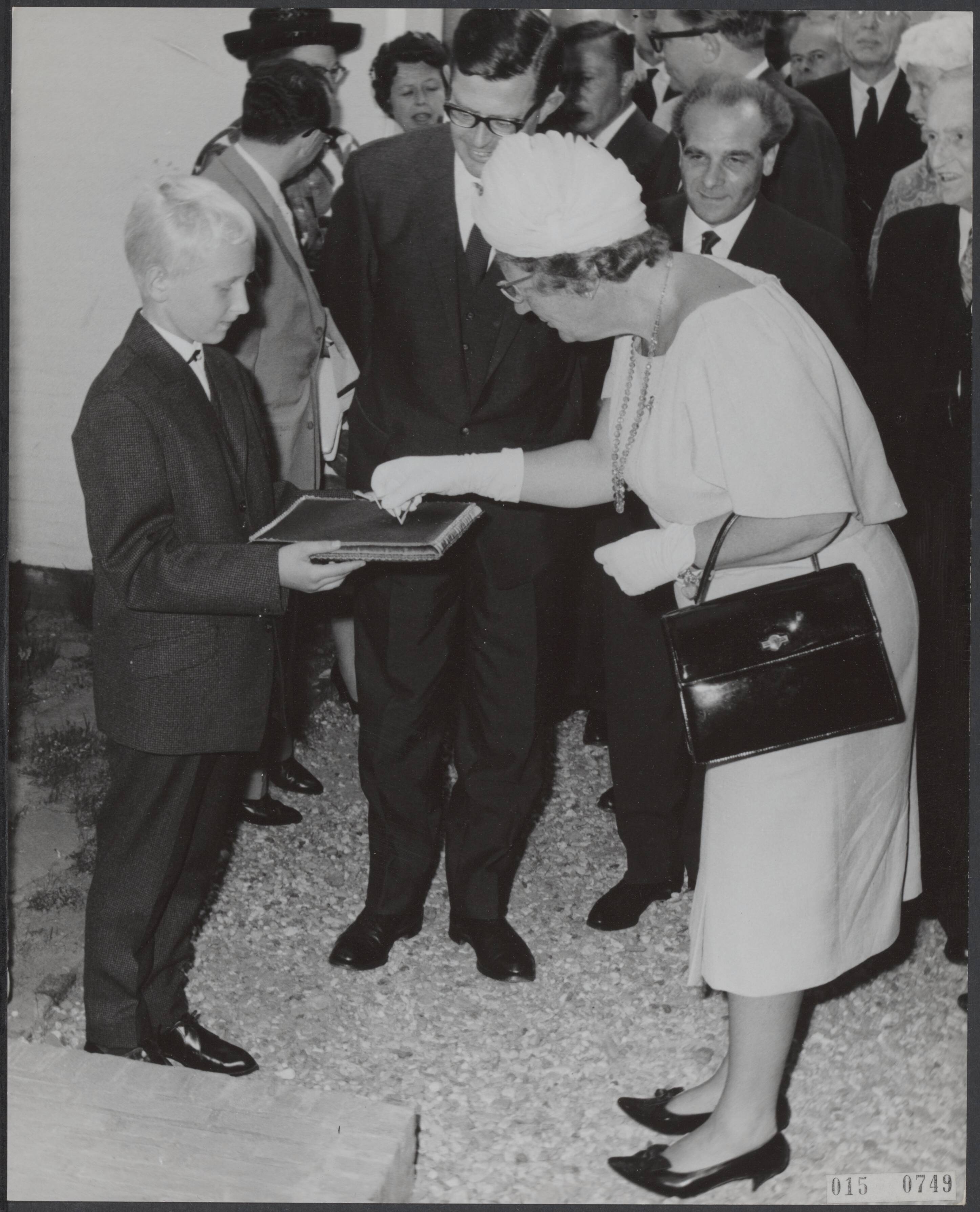 Fotocollectie Elsevier Binnenland — Koningin Juliana heeft in Huizen het eerste centrum voor de behandeling van hemofiliepatiënten geopend. Egon Spaargaren uit Amsterdam, een van de patiëntjes, bood haar een vergulde sleutel aan om het gebouw te openen — Foto: Nijs, Jac. de / Anefo. Licentie: Set B: Rechtenvrij / Publiek Domein. Bron: Nationaal Archief. http://hdl.handle.net/10648/adb60854-d0b4-102d-bcf8-003048976d84