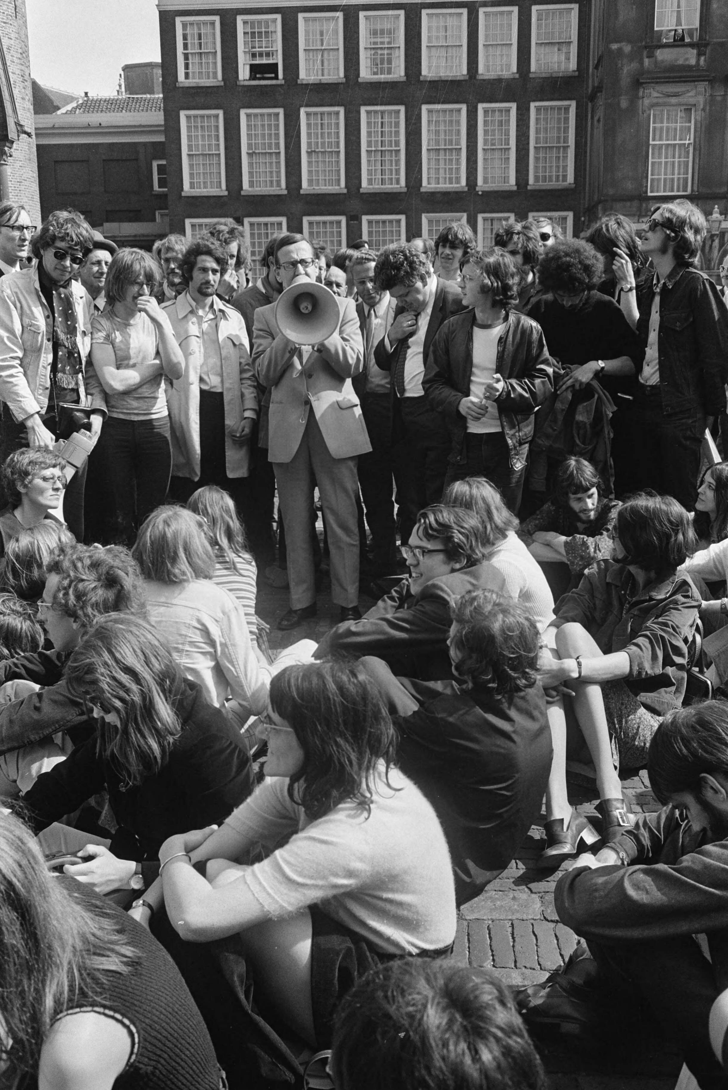 Fotocollectie Anefo — Studenten en leden van Wetenschappelijke Staf van Universiteit van Amsterdam, demonstreren tegen beleid van minister Veringa in Den Haag ; studenten zitten op — Foto: Koch, Eric / Anefo. Licentie: Set B: Rechtenvrij / Publiek Domein. Bron: Nationaal Archief. http://hdl.handle.net/10648/ab96ee1c-d0b4-102d-bcf8-003048976d84
