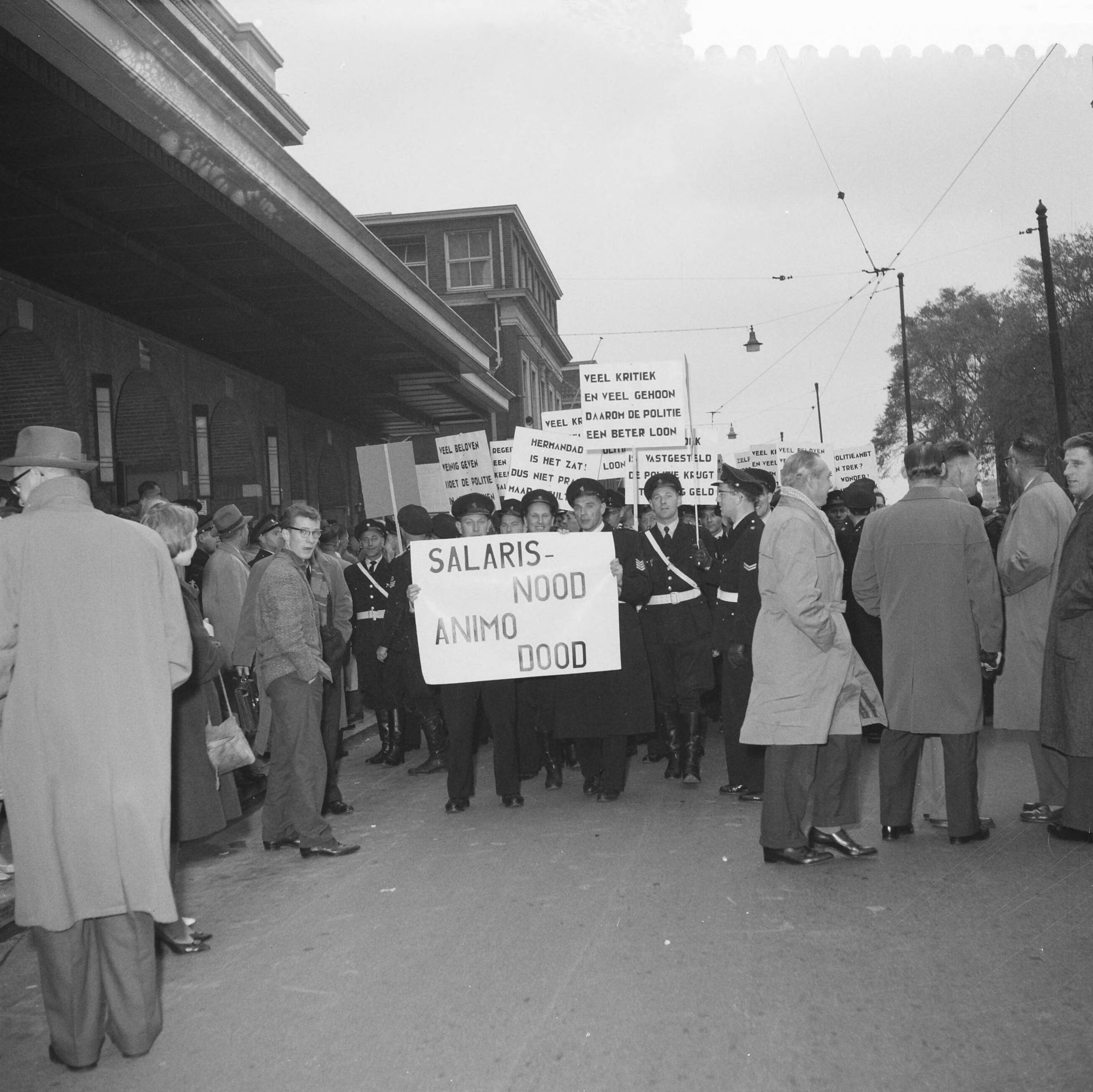 Fotocollectie Anefo — Protestvergadering door politie-ambtenaren tegen loonpolitiek van de regering in het gebouw voor Kunsten en Wetenschappen te Den Haag — Foto: Pot, Harry / Anefo. Licentie: Set B: Rechtenvrij / Publiek Domein. Bron: Nationaal Archief. http://hdl.handle.net/10648/a9bc3dc2-d0b4-102d-bcf8-003048976d84