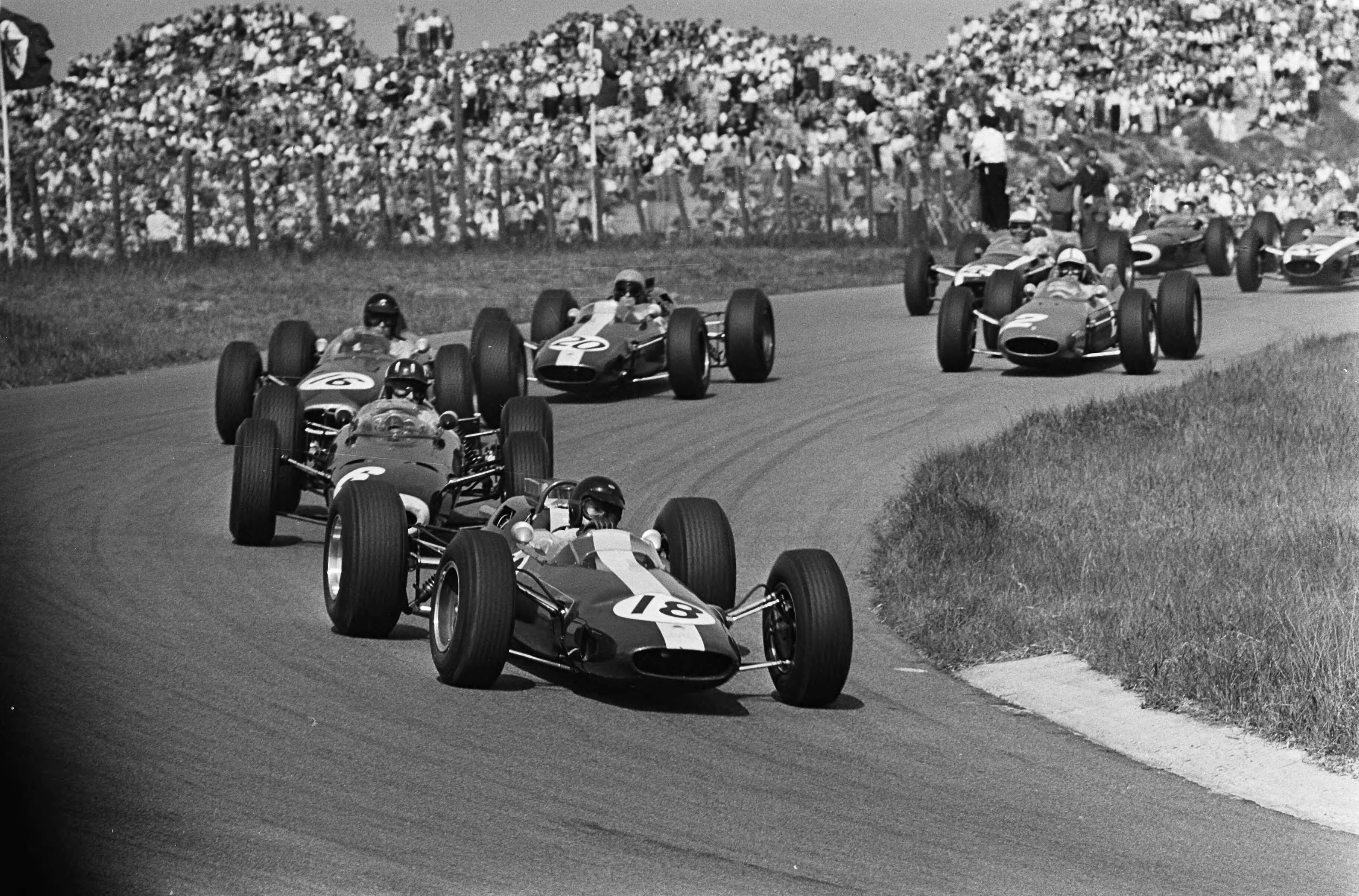 Fotocollectie Anefo — Grand Prix van Nederland, het rennersveld in de bocht aan kop Jim Clark met achter no. 6 Graham Hill , no. 16 Dan Gurney en no. 20 Peter Arundell / — Foto: Pot, Harry / Anefo. Licentie: Set B: Rechtenvrij / Publiek Domein. Bron: Nationaal Archief. http://hdl.handle.net/10648/aa6a633e-d0b4-102d-bcf8-003048976d84