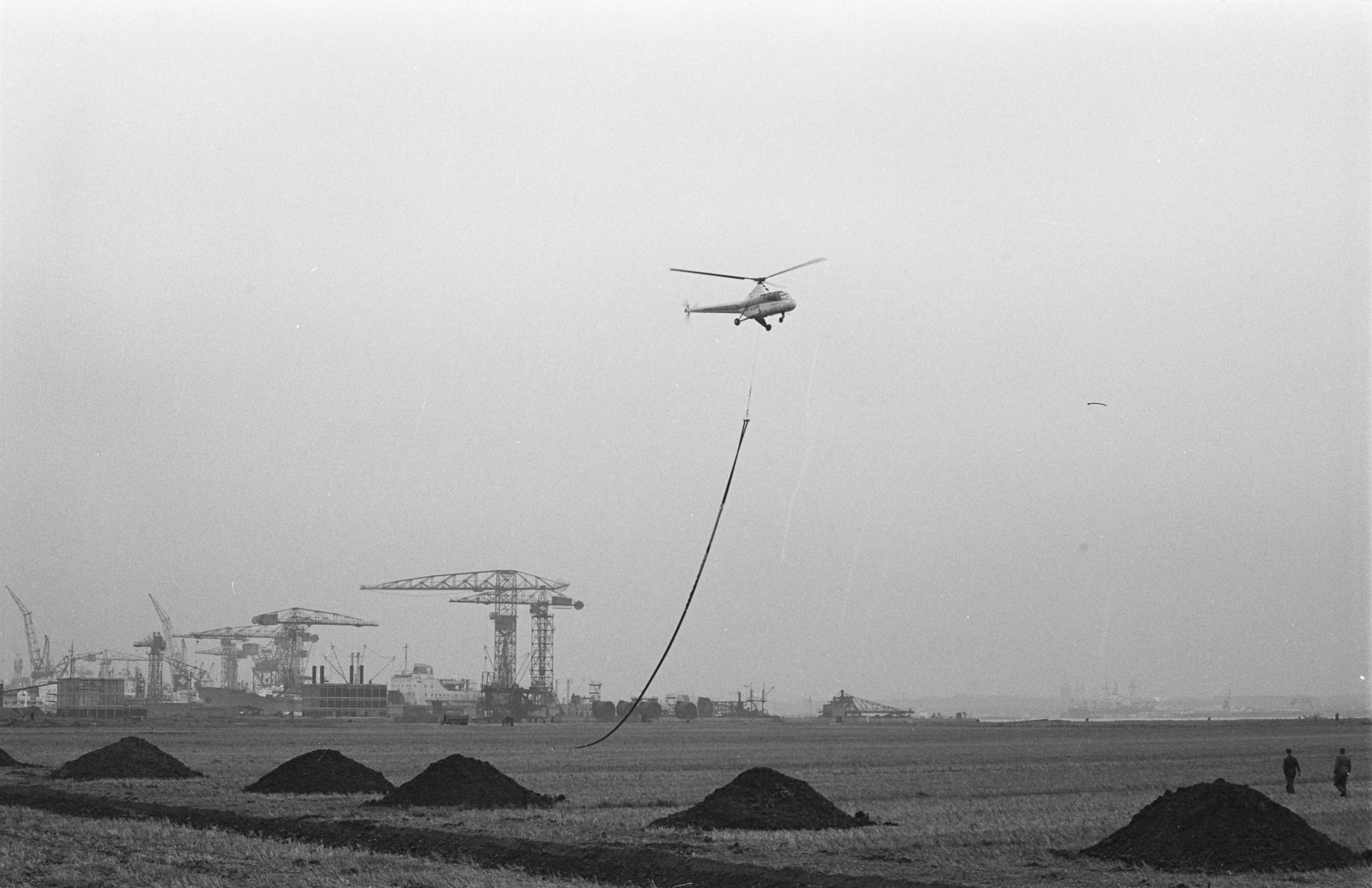 Fotocollectie Anefo — Buisvervoer per helicopter in Amsterdam-Noord tijdens bouwwerkzaamheden — Foto: Rossem, Wim van / Anefo. Licentie: Set B: Rechtenvrij / Publiek Domein. Bron: Nationaal Archief. http://hdl.handle.net/10648/a9f5cdb2-d0b4-102d-bcf8-003048976d84