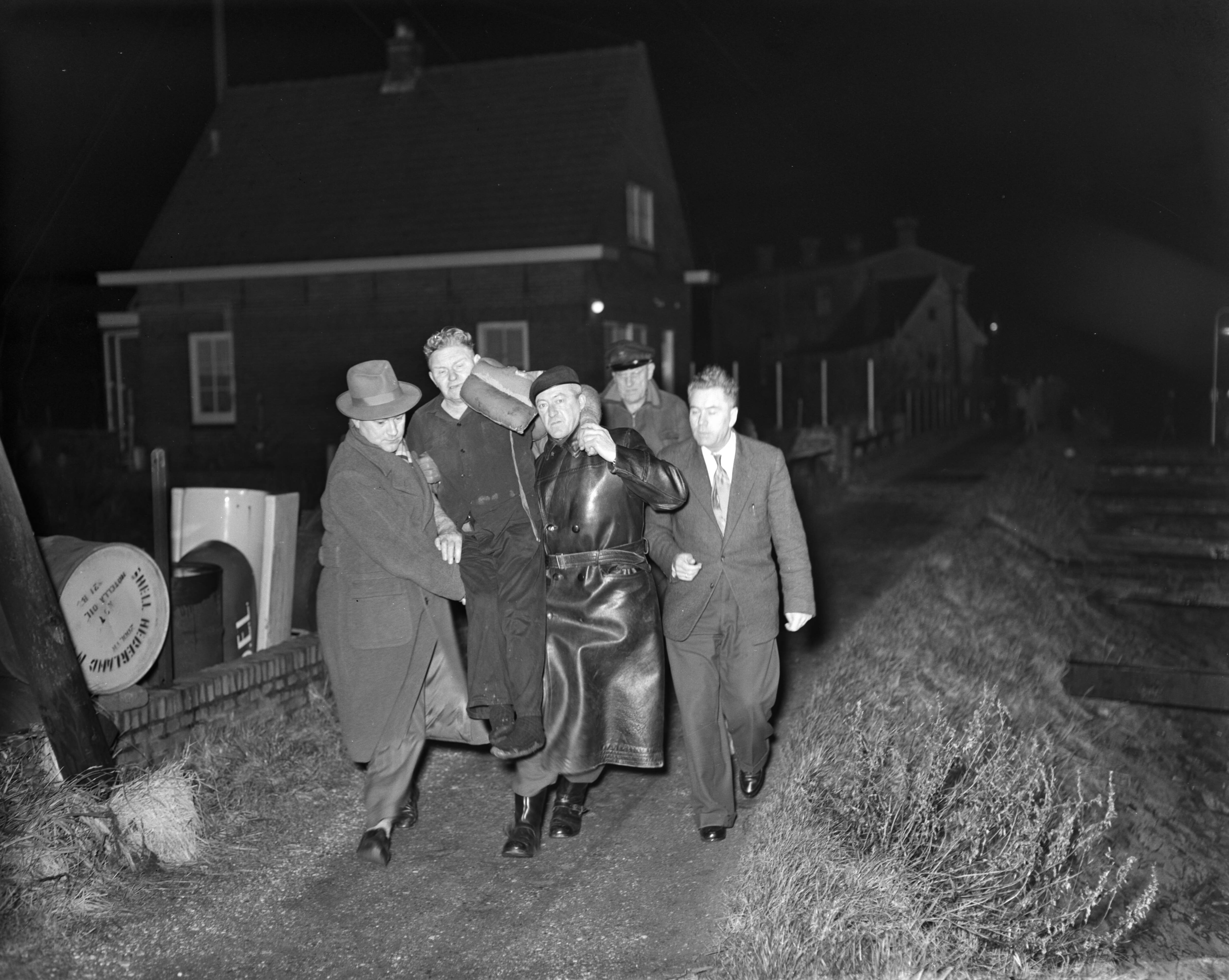 Fotocollectie Anefo — Aan land brengen van gereddenen van de zeesleper "Ebro", die bij Schouwen-Duiveland is vergaan. Tweede machinist D.A. Vroomhout liet zich van zeven meter hoogte vallen .. . naast het vangnet. Hij brak daarbij zijn mlddelvoetsbeenderen. Zijn redders droegen hem ln Veere aan wal. Hij is opgenomen in het ziekenhuis te Vlissingen — Foto: Behrens, Herbert F. / Anefo. Licentie: Set B: Rechtenvrij / Publiek Domein. Bron: Nationaal Archief. http://hdl.handle.net/10648/a972a19e-d0b4-102d-bcf8-003048976d84