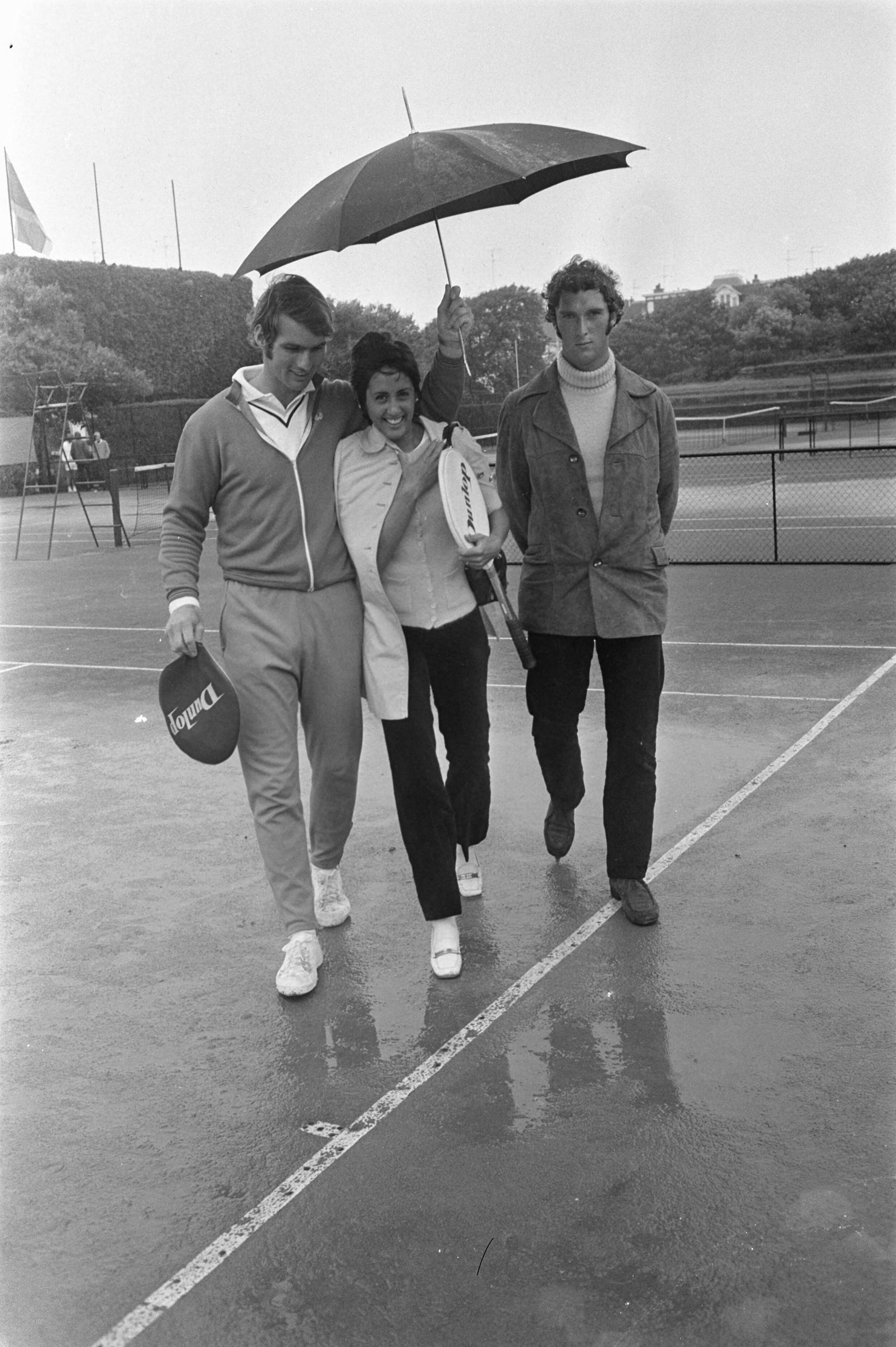 Fotocollectie Anefo — Nationale tenniskampioenschappen op METS-banen Scheveningen; Fred Hemmes, Judith Salome, Jan Hordijk met paraplu — Foto: Koch, Eric / Anefo. Licentie: Set B: Rechtenvrij / Publiek Domein. Bron: Nationaal Archief. http://hdl.handle.net/10648/ab9f2de8-d0b4-102d-bcf8-003048976d84