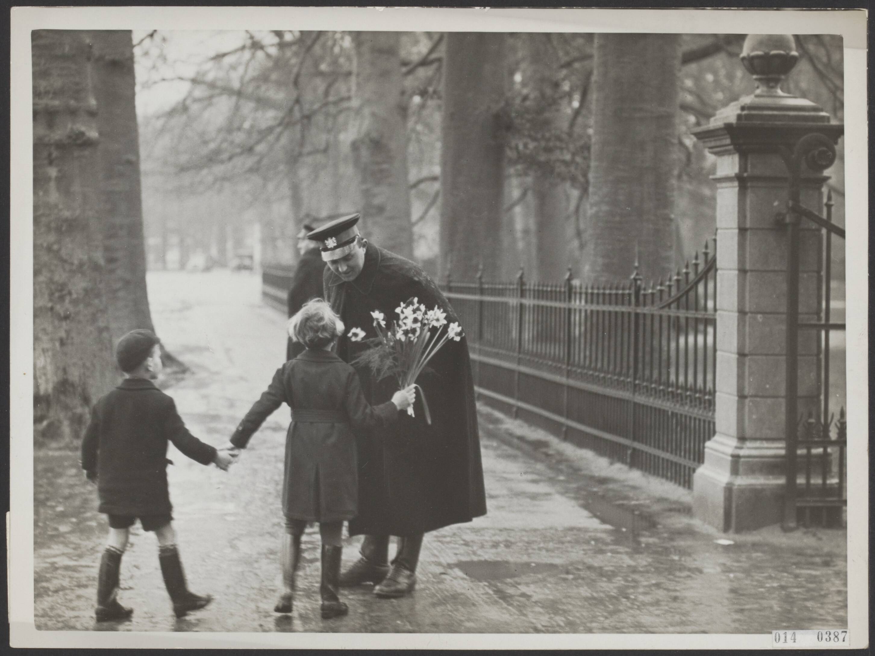 Fotocollectie Elsevier Binnenland — Bij de toegangspoort van Paleis Soestdijk vragen twee jeugdige ingezetenen van Baarn, n.l. Marianne en Kees Romijn, aan de dienstdoende veldwachter om toegang tot het Paleis. Zij willen prinses Juliana en prins Bernhard een bos bloemen aanbieden vanwege hun terugkomst op het Paleis — Foto: N.V. Polygoon. Licentie: Set B: Rechtenvrij / Publiek Domein. Bron: Nationaal Archief. http://hdl.handle.net/10648/adb07a6a-d0b4-102d-bcf8-003048976d84
