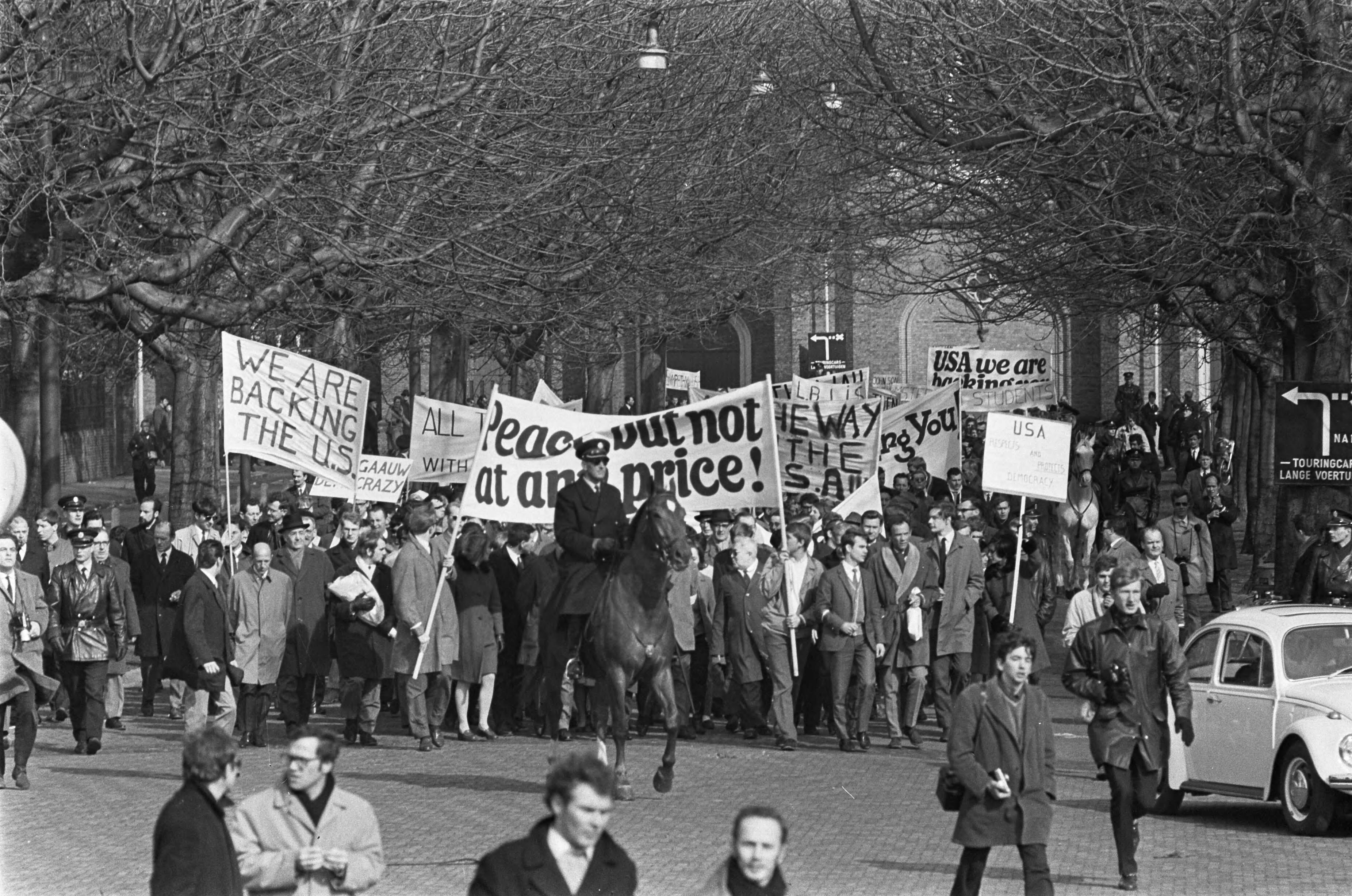 Fotocollectie Anefo — Pro Amerika demonstratie in Den Haag . Met vele spandoeken trekken ze door Den Haag — Foto: Koch, Eric / Anefo. Licentie: Set B: Rechtenvrij / Publiek Domein. Bron: Nationaal Archief. http://hdl.handle.net/10648/ab39b3b4-d0b4-102d-bcf8-003048976d84