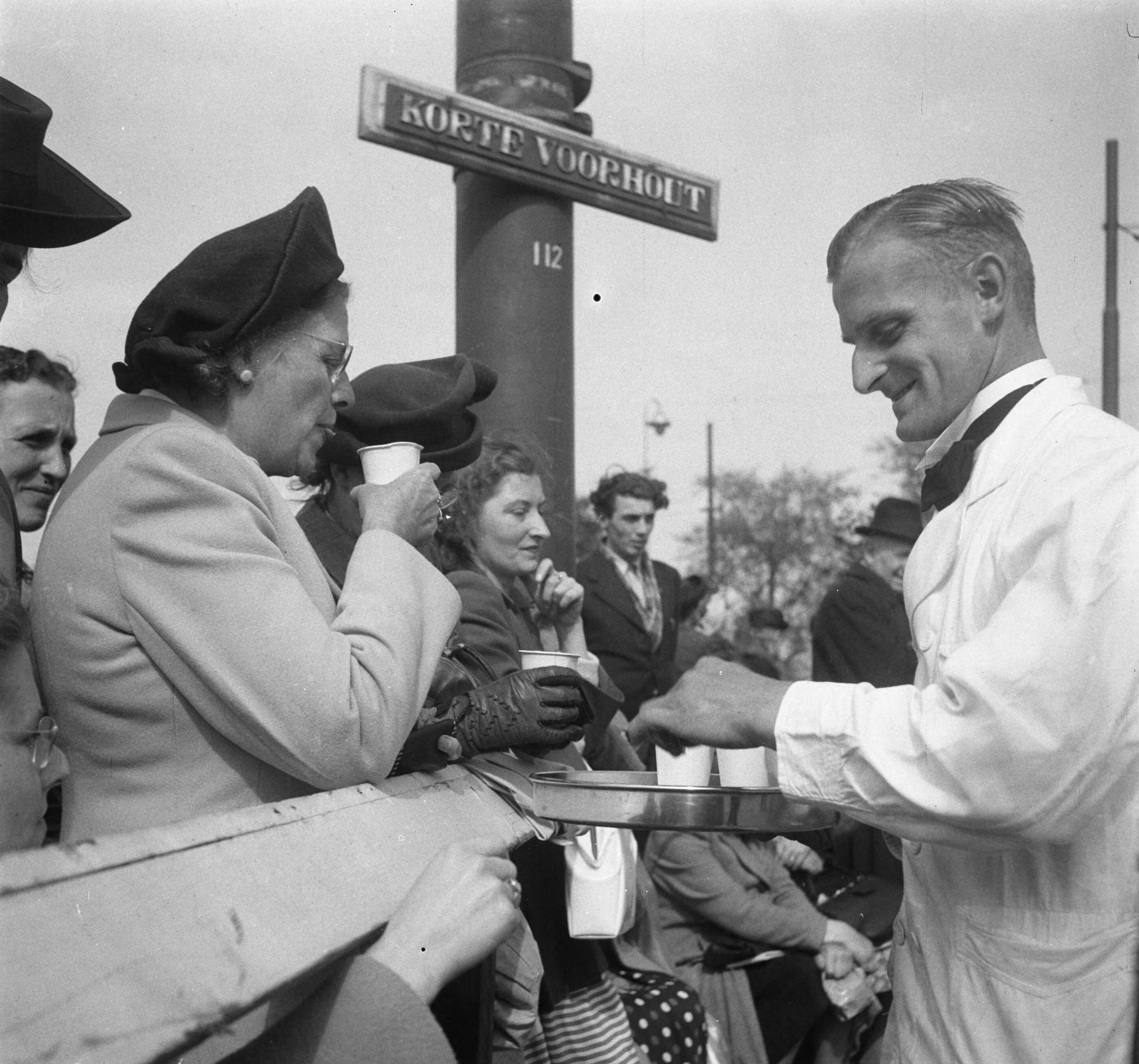 Intocht van koningin Juliana in Den Haag (1948) — Intocht Koningin Juliana in Den Haag. Verkoop bekers met koffie op het Korte Voorhout — Foto: Steenkamp, B.J.J. (Ben) / Anefo. Licentie: Set B: Rechtenvrij / Publiek Domein. Bron: Nationaal Archief. http://hdl.handle.net/10648/a8bd42fe-d0b4-102d-bcf8-003048976d84