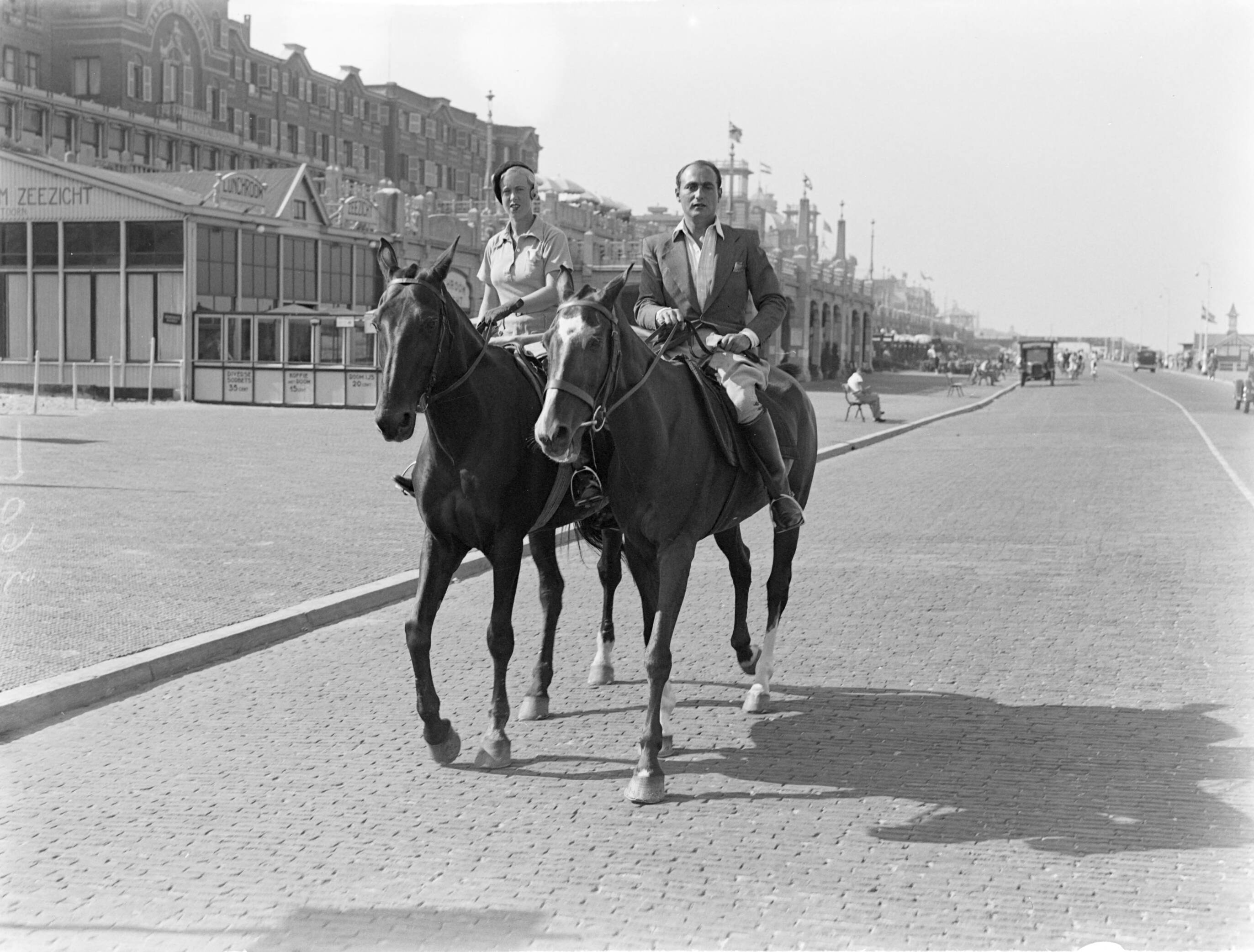 Scheveningen. — Een man (Farrar?) en een vrouw (Yvonne?) te paard aan de Scheveningse boulevard — Foto: Poll, Willem van de. Licentie: Set B: Rechtenvrij / Publiek Domein. Bron: Nationaal Archief. http://hdl.handle.net/10648/ae9b1e12-d0b4-102d-bcf8-003048976d84