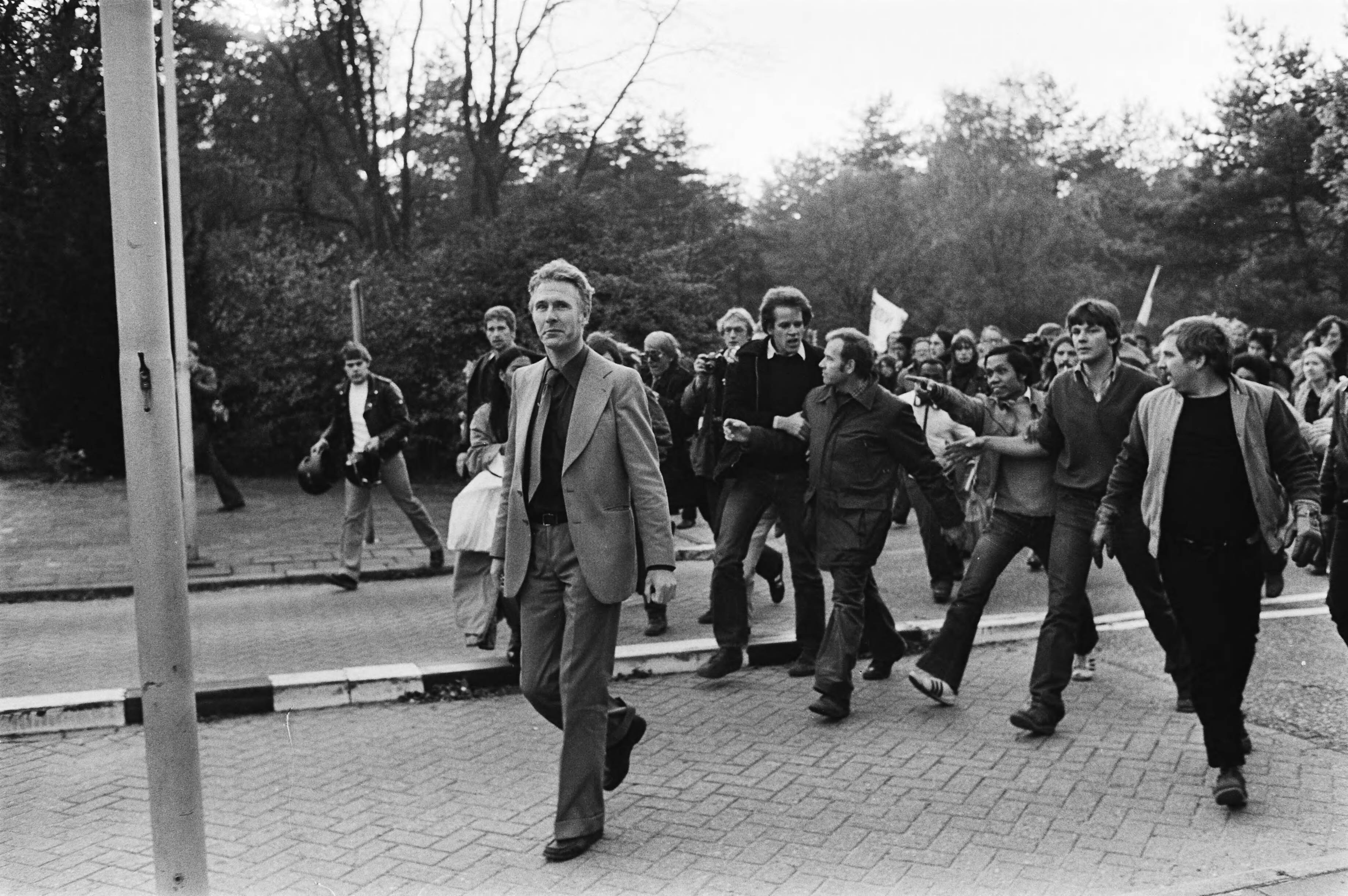 Manifestatie in de bossen van Soestduinen tegen het neofascisme — Joop Glimmerveen, leider van de Volksunie, gevolgd door voor- en tegenstanders — Foto: Suyk, Koen / Anefo. Licentie: Set B: Rechtenvrij / Publiek Domein. Bron: Nationaal Archief. http://hdl.handle.net/10648/acd3aab8-d0b4-102d-bcf8-003048976d84