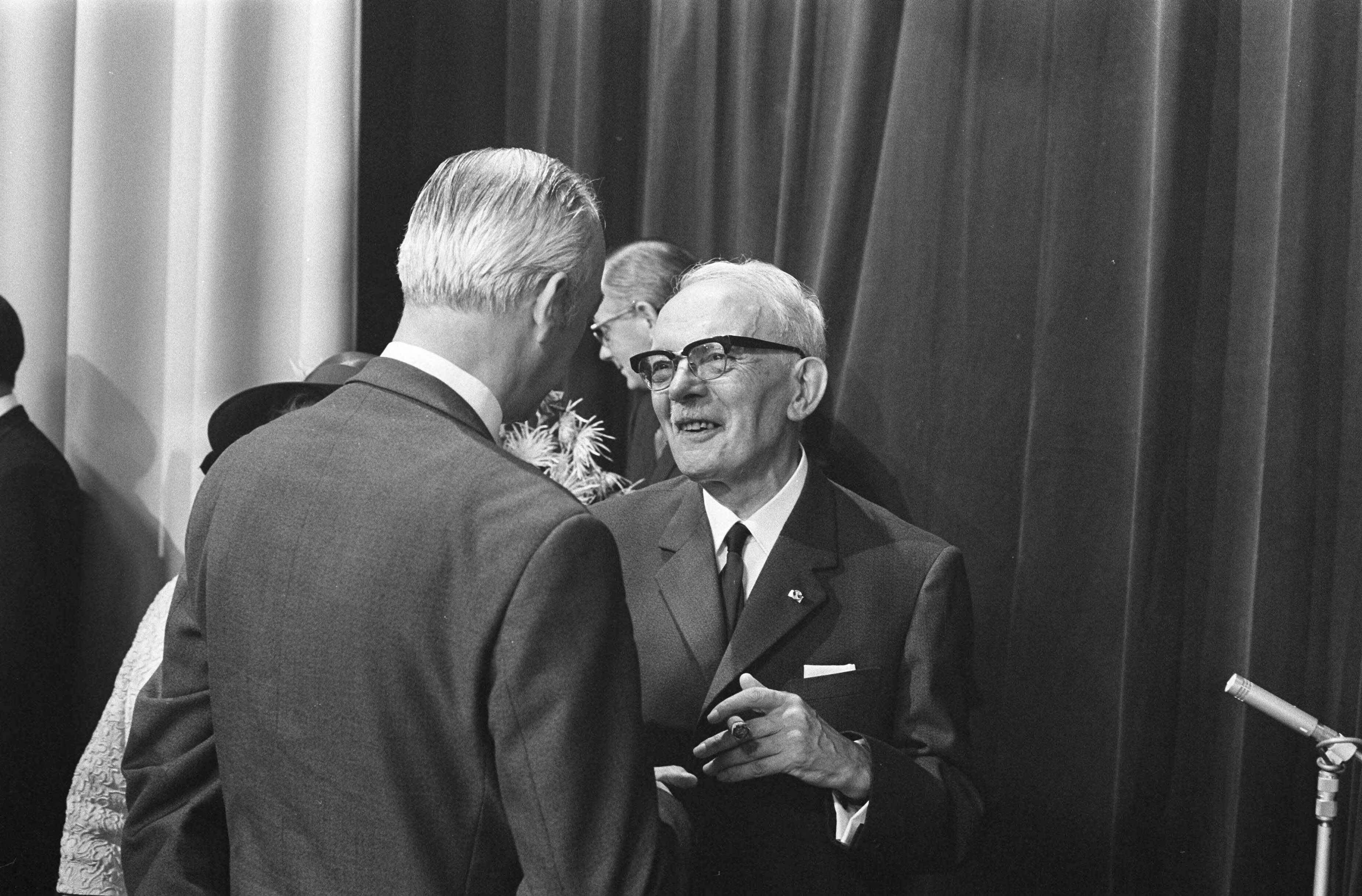 Fotocollectie Anefo — Minister Klompe installeert bestuur van Nederlandse Omroep Stichting, Hilversum tijdens receptie links Karel Prior (TROS) en rechts mr. Roosjes met echtgenote / — Foto: Verhoeff, Bert / Anefo. Licentie: Set B: Rechtenvrij / Publiek Domein. Bron: Nationaal Archief. http://hdl.handle.net/10648/ab6bfd88-d0b4-102d-bcf8-003048976d84