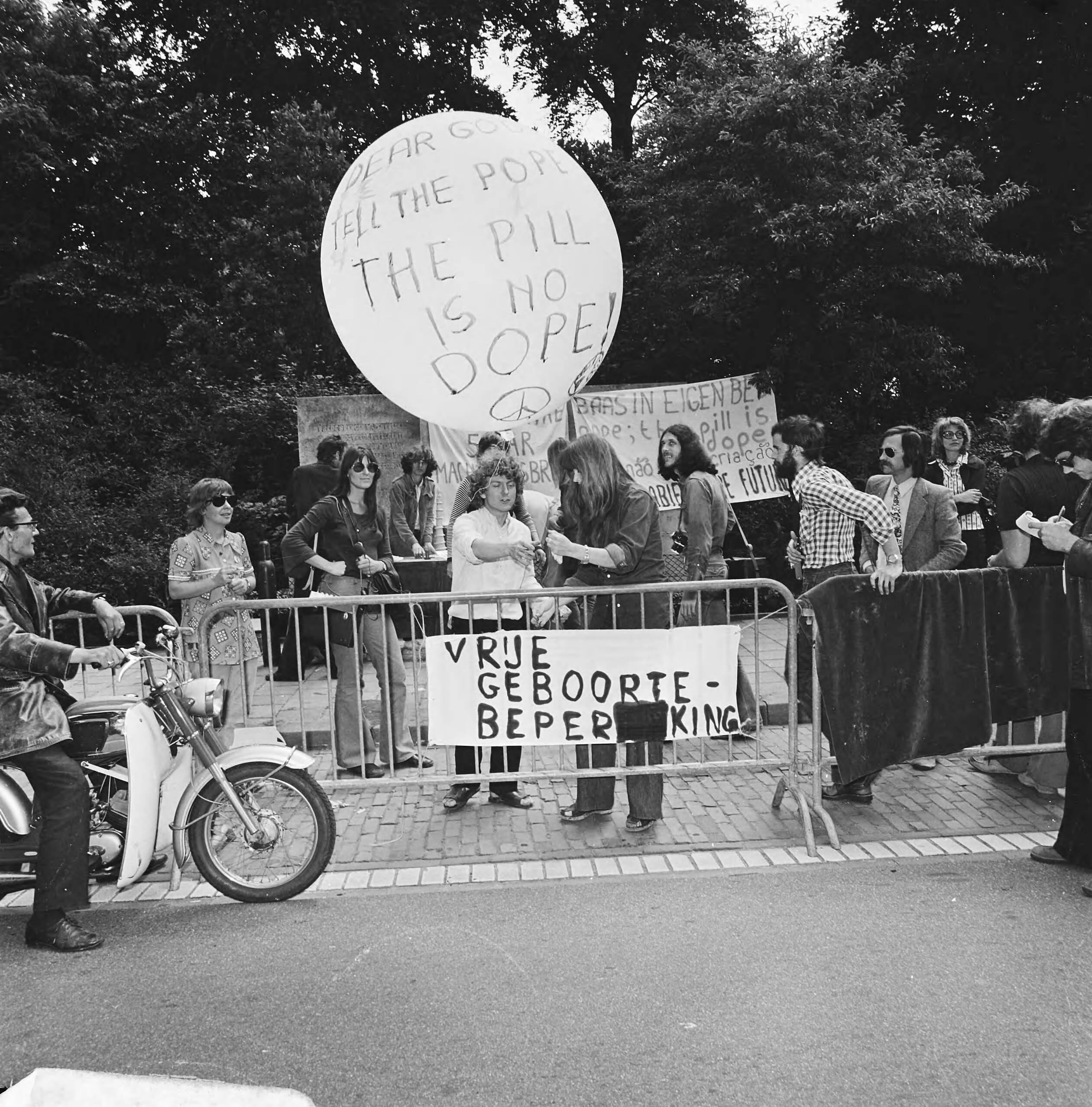 Fotocollectie Anefo — Dolle Mina beweging te Den Haag tegen voorschriften geboortebeperking RK-kerk, ballon wordt opgelaten Dear god tell pope pill is no dope — Foto: Mieremet, Rob / Anefo. Licentie: Set B: Rechtenvrij / Publiek Domein. Bron: Nationaal Archief. http://hdl.handle.net/10648/ac327e36-d0b4-102d-bcf8-003048976d84