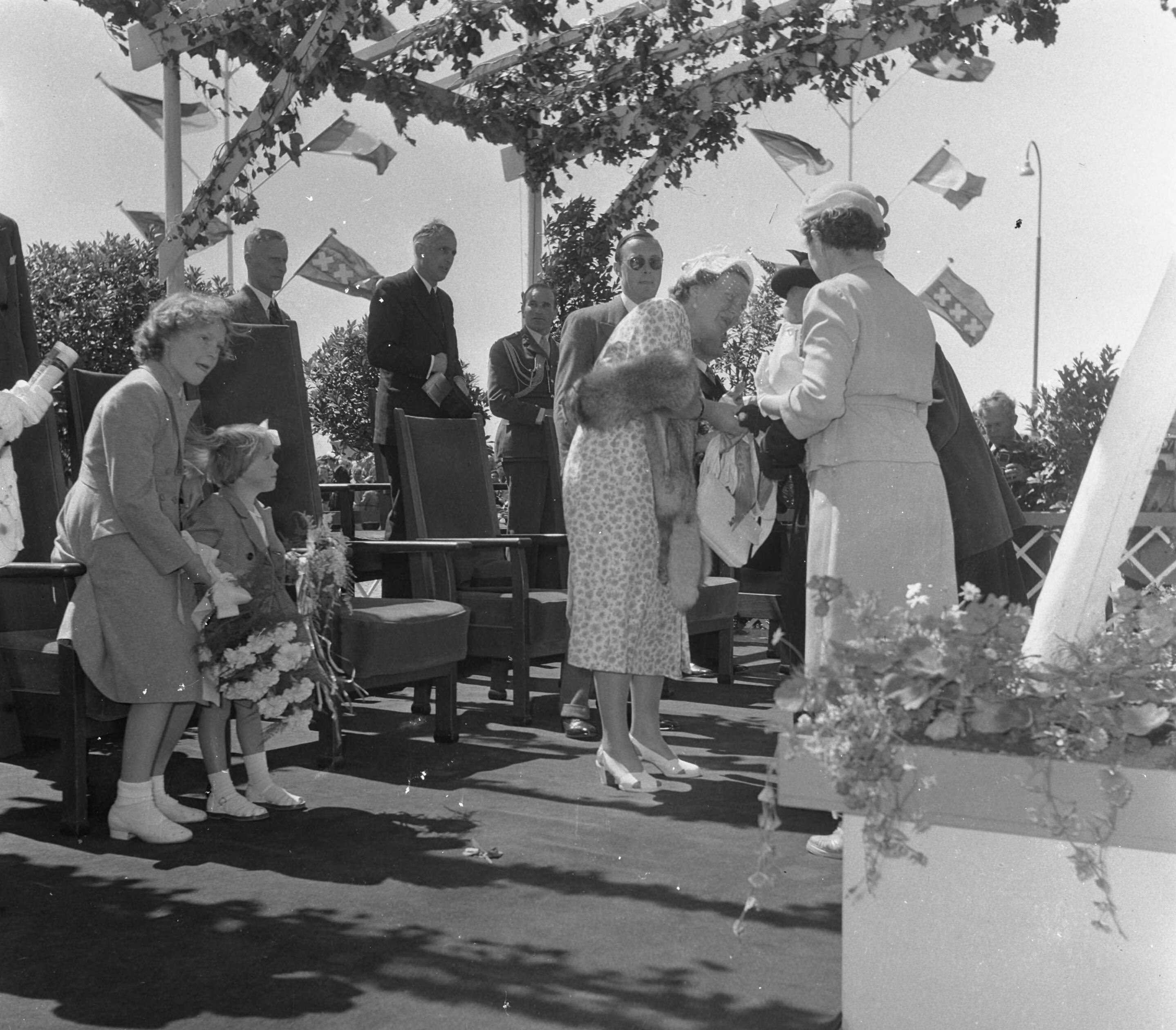 Fotocollectie Anefo — Opening sluis in Tiel. Koningin Juliana krijgt bloemen aangeboden. Links prinses Irene en prinses Marijke (Christina) — Foto: Noske, J.D. / Anefo. Licentie: Set B: Rechtenvrij / Publiek Domein. Bron: Nationaal Archief. http://hdl.handle.net/10648/a8fa3e16-d0b4-102d-bcf8-003048976d84