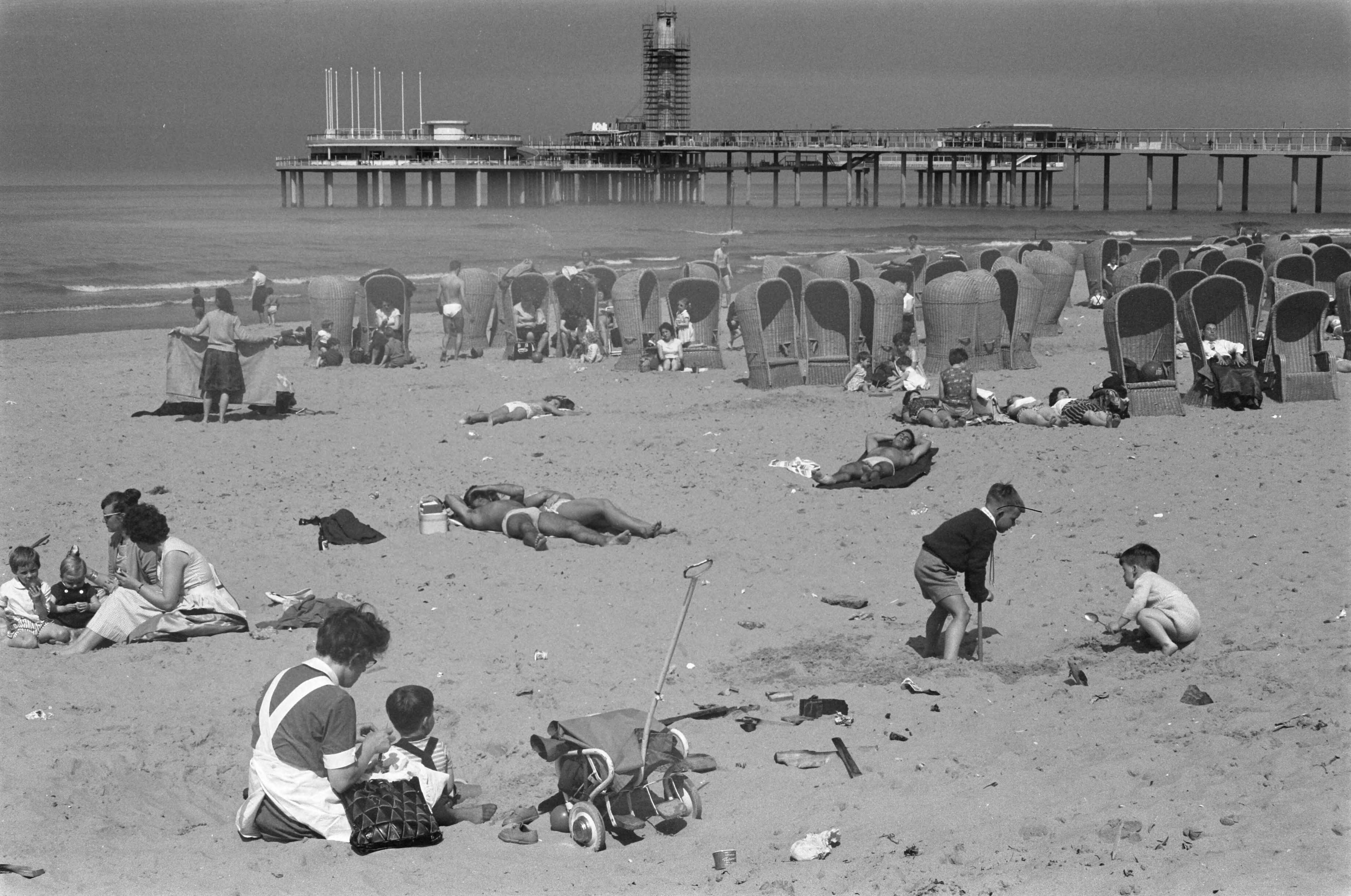 Fotocollectie Anefo — De nieuwe Pier in Scheveningen. Strandbeeld met in de achtergrond de nieuwe pier in aanbouw — Foto: Pot, Harry / Anefo. Licentie: Set B: Rechtenvrij / Publiek Domein. Bron: Nationaal Archief. http://hdl.handle.net/10648/a9d2e414-d0b4-102d-bcf8-003048976d84