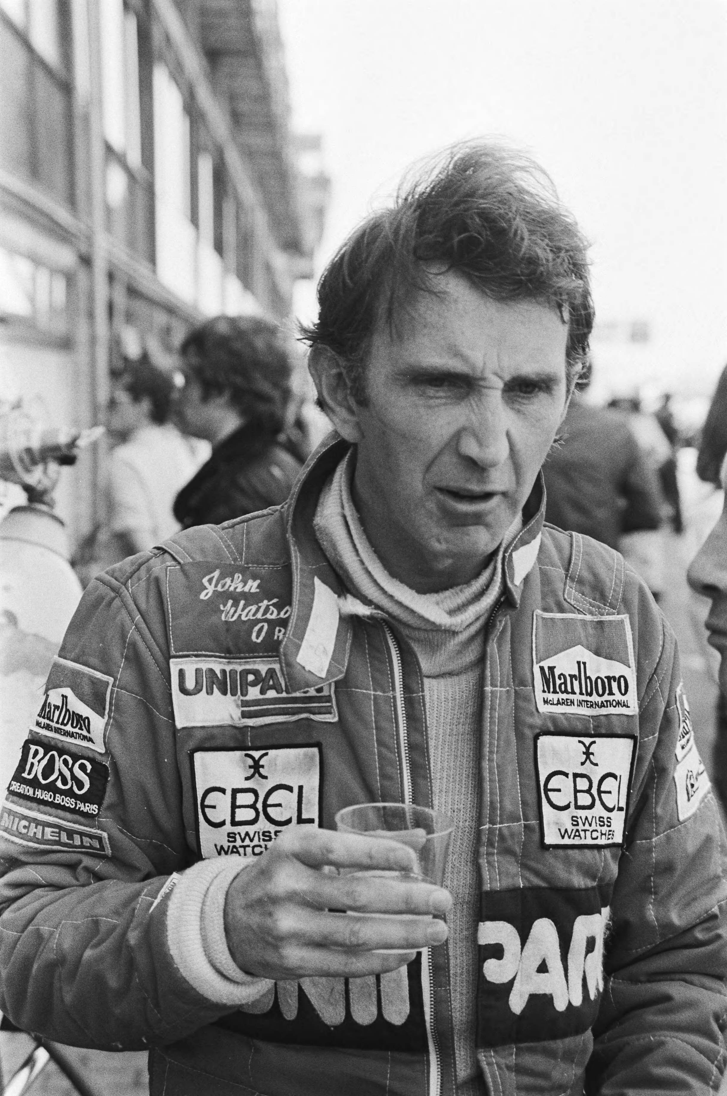 Fotocollectie Anefo — Grand Pris van Nederland te Zandvoort; koppen coureurs, John Watson — Foto: Dijk, Hans van / Anefo. Licentie: Set B: Rechtenvrij / Publiek Domein. Bron: Nationaal Archief. http://hdl.handle.net/10648/ad1abf02-d0b4-102d-bcf8-003048976d84