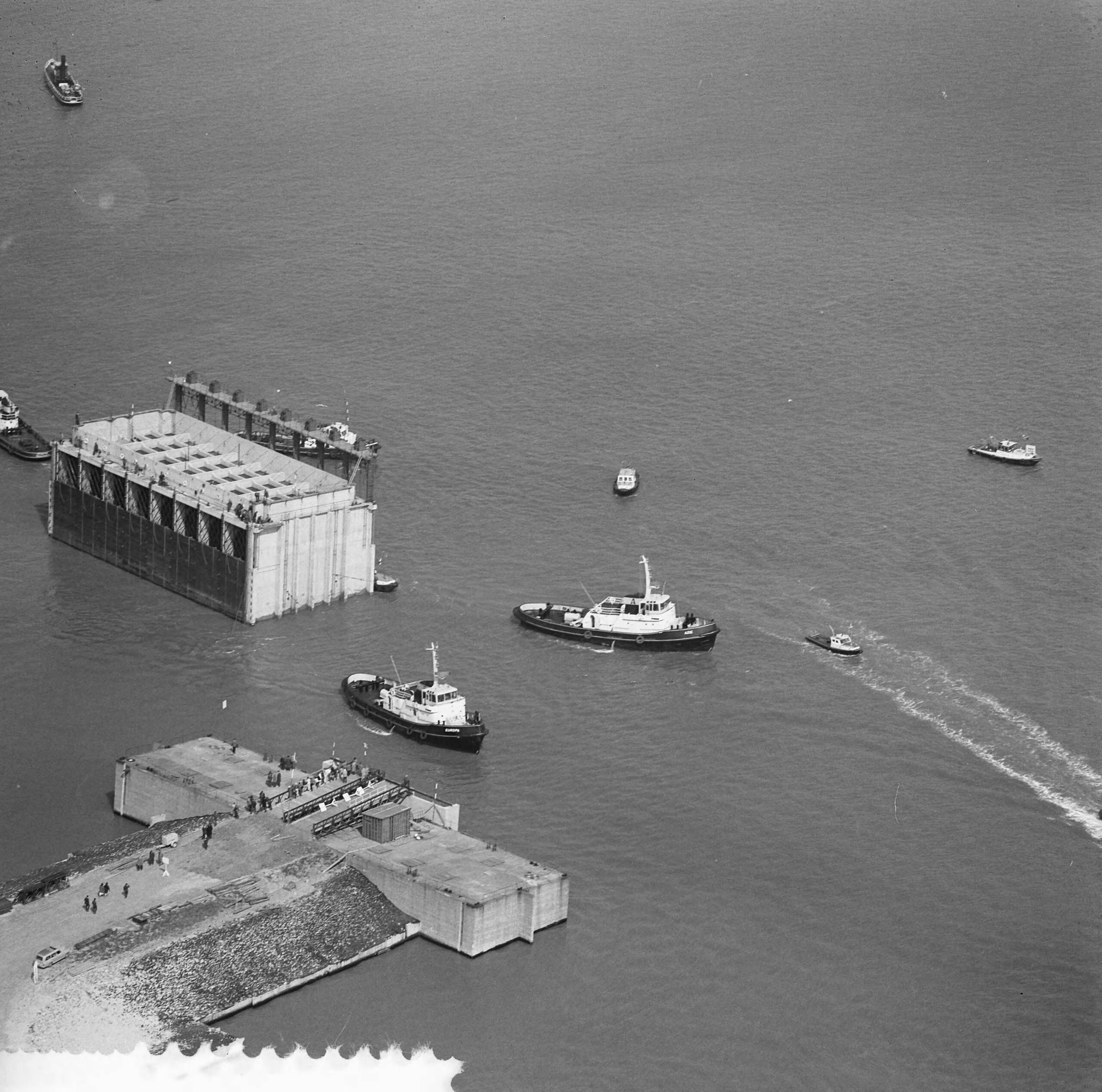 Fotocollectie Anefo — Luchtopnamen. Invaren van caissons in het Veerse Gat — Foto: Slagboom, Anton / Anefo. Licentie: Set B: Rechtenvrij / Publiek Domein. Bron: Nationaal Archief. http://hdl.handle.net/10648/a9d10c70-d0b4-102d-bcf8-003048976d84