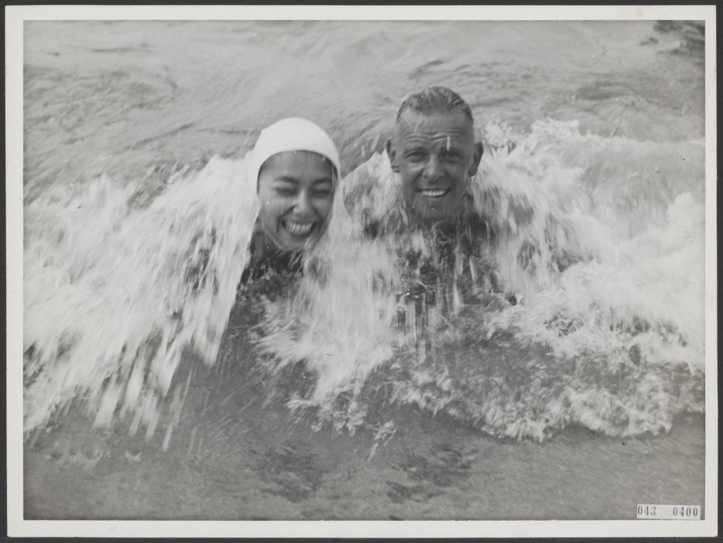 Fotocollectie Elsevier Binnenland — [Serie "Summum". over vermaak in Scheveningen] [Man en vrouw met badmuts in de golven] — Foto: Associated Correspondents. Licentie: Set B: Rechtenvrij / Publiek Domein. Bron: Nationaal Archief. http://hdl.handle.net/10648/adf8e1ba-d0b4-102d-bcf8-003048976d84