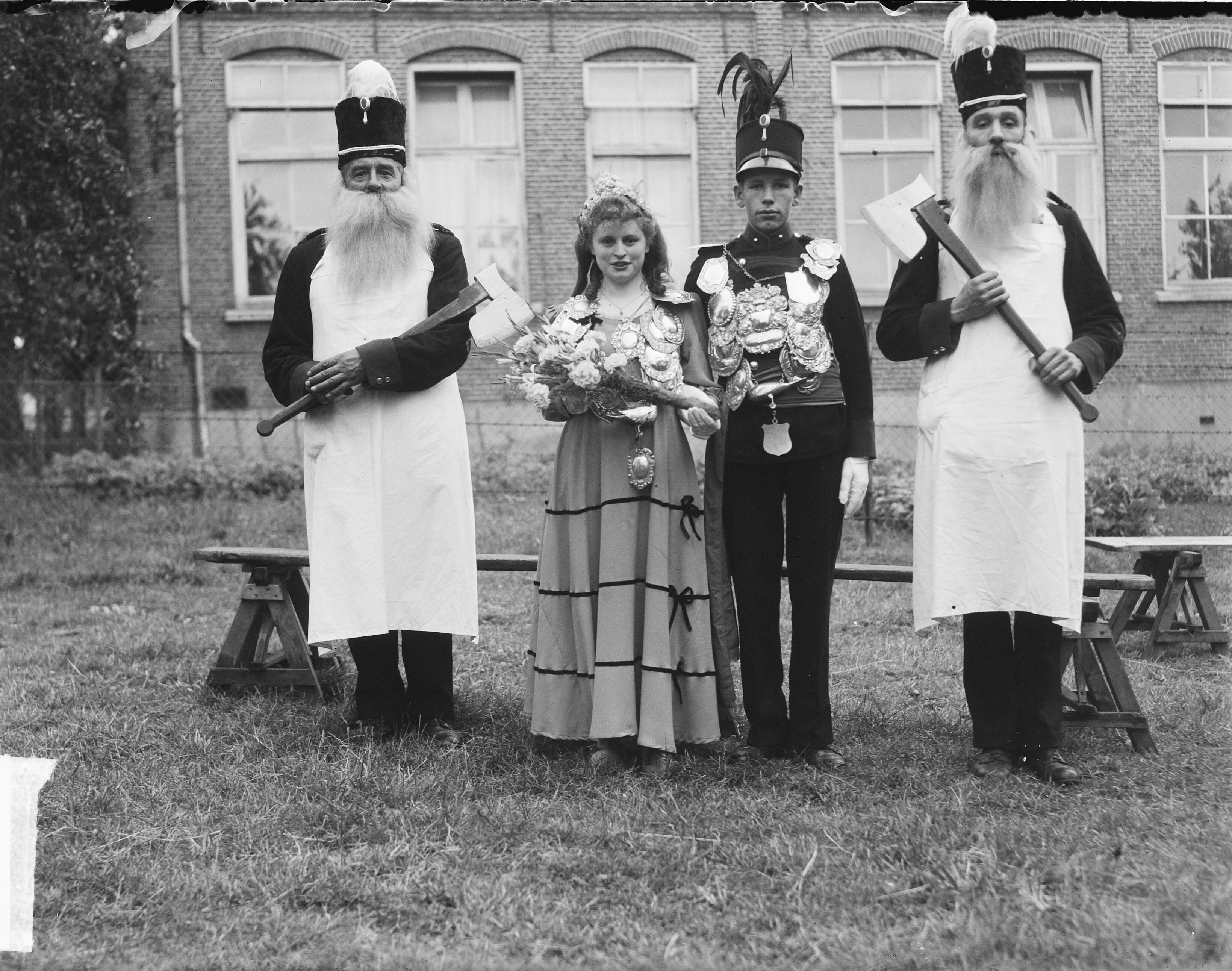 300-jarig bestaan schutterij St. Bavo — 300-jarig bestaan schutterij St. Bavo. [Een jonge schutterskoning en koningin poseren met aan weerszijden z.g. Bielemannen met valse baarden] — Foto: Oorschot, […] van / Anefo. Licentie: Set B: Rechtenvrij / Publiek Domein. Bron: Nationaal Archief. http://hdl.handle.net/10648/a8daf326-d0b4-102d-bcf8-003048976d84