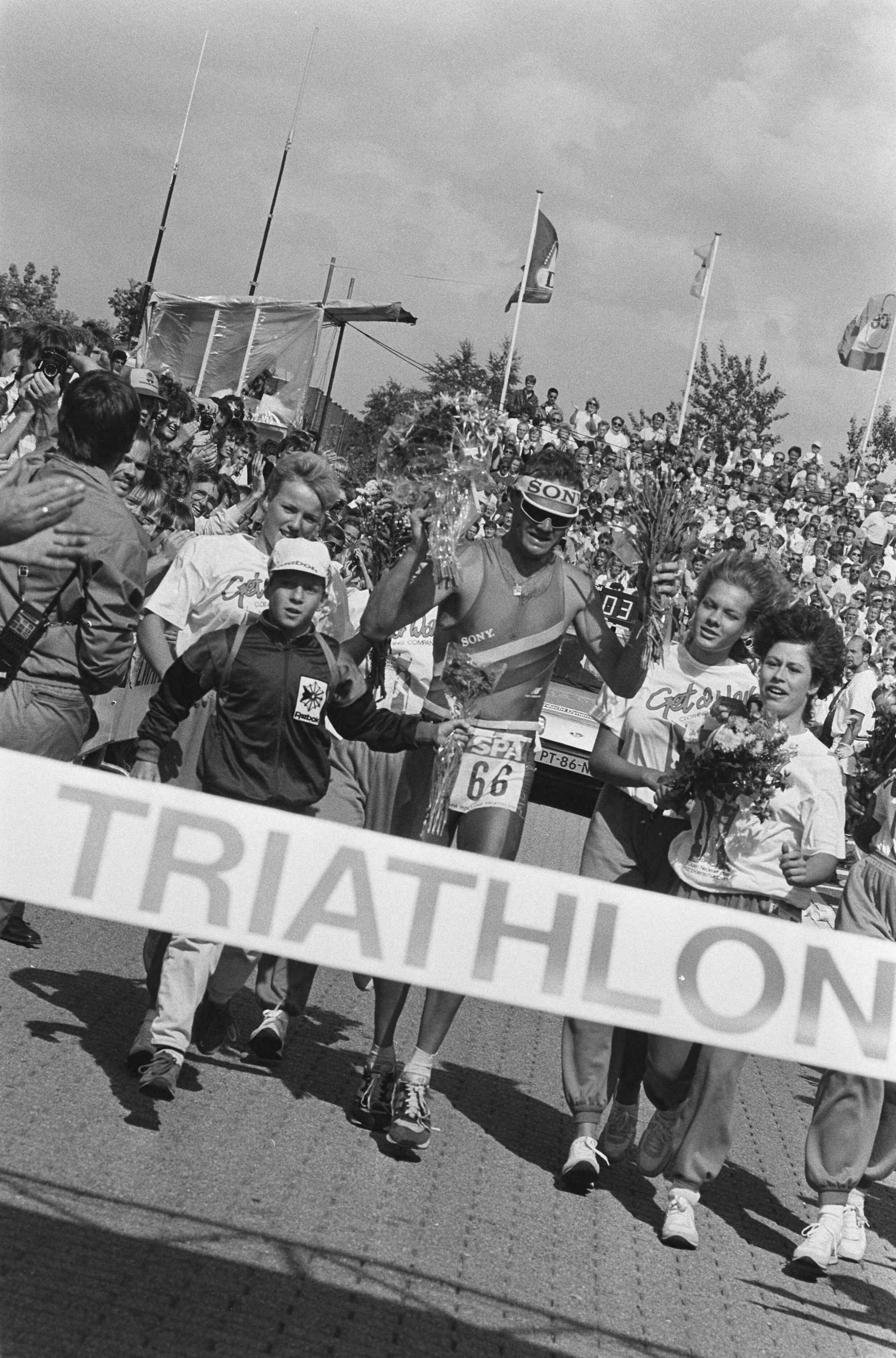 Fotocollectie Anefo — Holland Triathlon 1986 in Almere; finish van winnaar Axel Koenders — Foto: Bogaerts, Rob / Anefo. Licentie: Set B: Rechtenvrij / Publiek Domein. Bron: Nationaal Archief. http://hdl.handle.net/10648/ad562c5e-d0b4-102d-bcf8-003048976d84