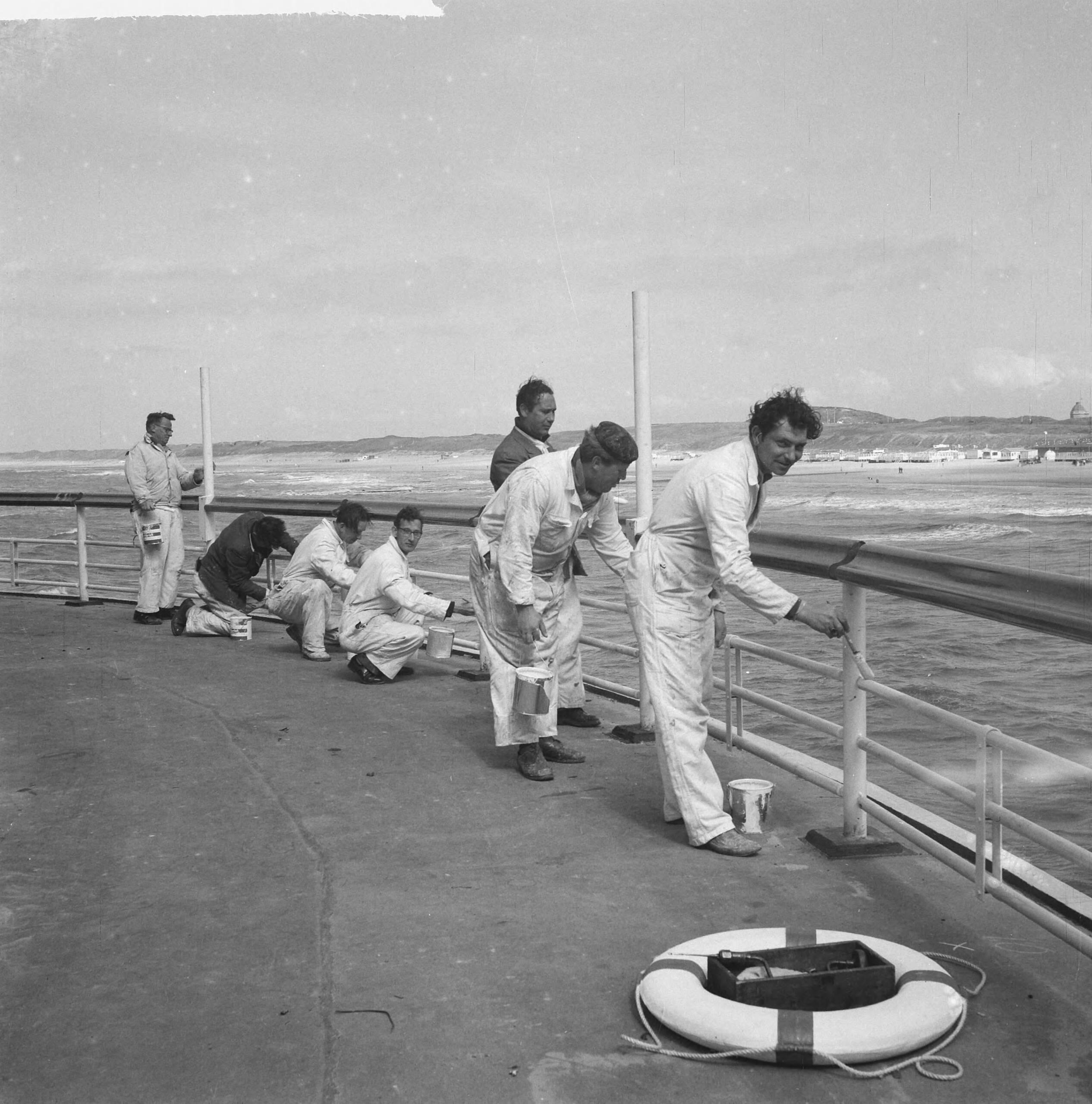 Nieuwe Pier in Scheveningen — Nieuwe Pier in Scheveningen. Arbeiders schilderen omheining — Foto: Nijs, Jac. de / Anefo. Licentie: Set B: Rechtenvrij / Publiek Domein. Bron: Nationaal Archief. http://hdl.handle.net/10648/a9d5ae60-d0b4-102d-bcf8-003048976d84