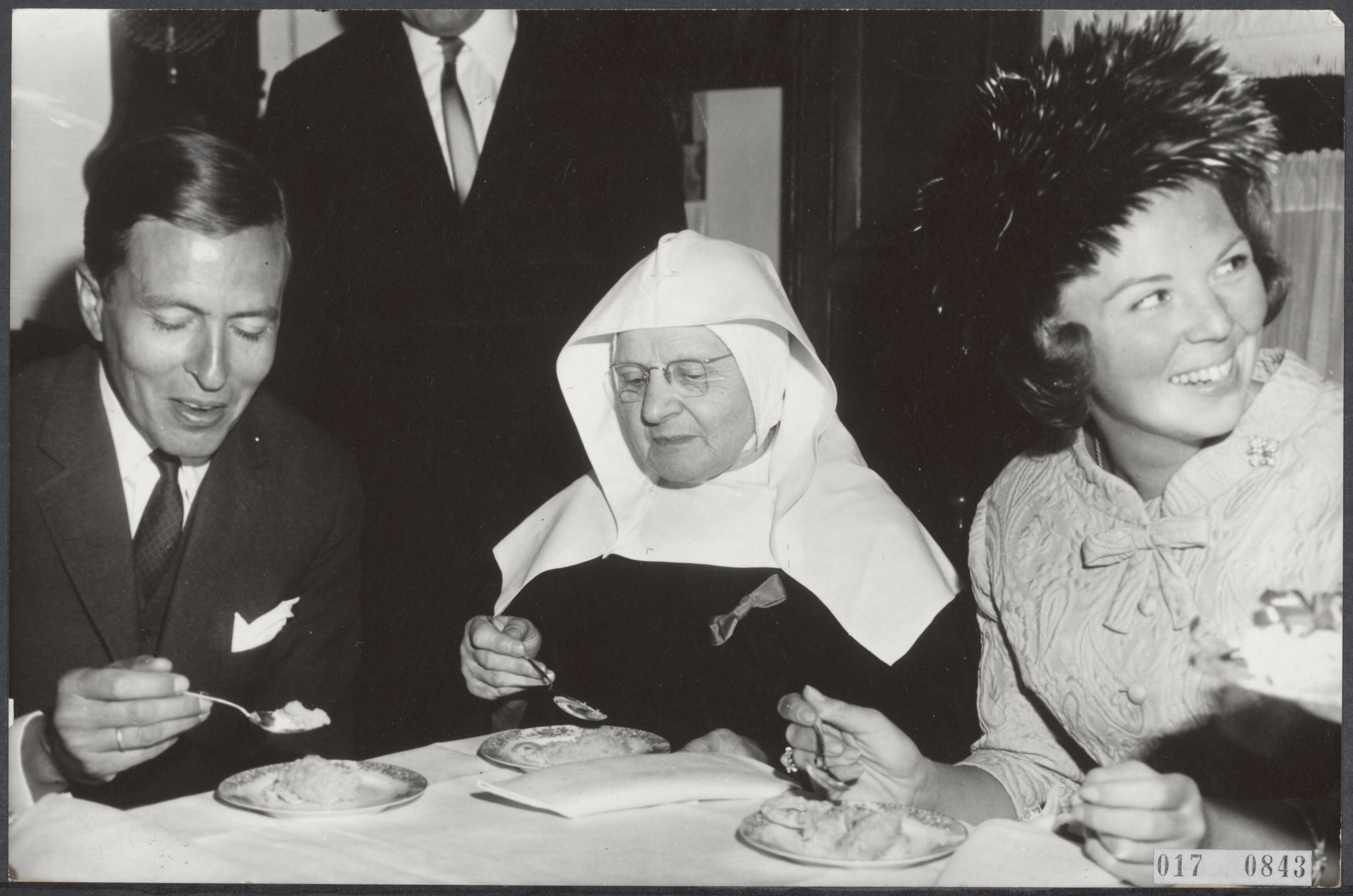 Fotocollectie Elsevier Binnenland — Bezoek van prinses Beatrix en prins Claus aan Breda. Zij brachten o.a. een bezoek aan het Begijnhof, waar traditiegetrouw een schaaltje met rijst werd genuttigd. In het midden een Begijntje — Foto: Bilsen, Joop van / Anefo. Licentie: Set B: Rechtenvrij / Publiek Domein. Bron: Nationaal Archief. http://hdl.handle.net/10648/adbf2f6a-d0b4-102d-bcf8-003048976d84