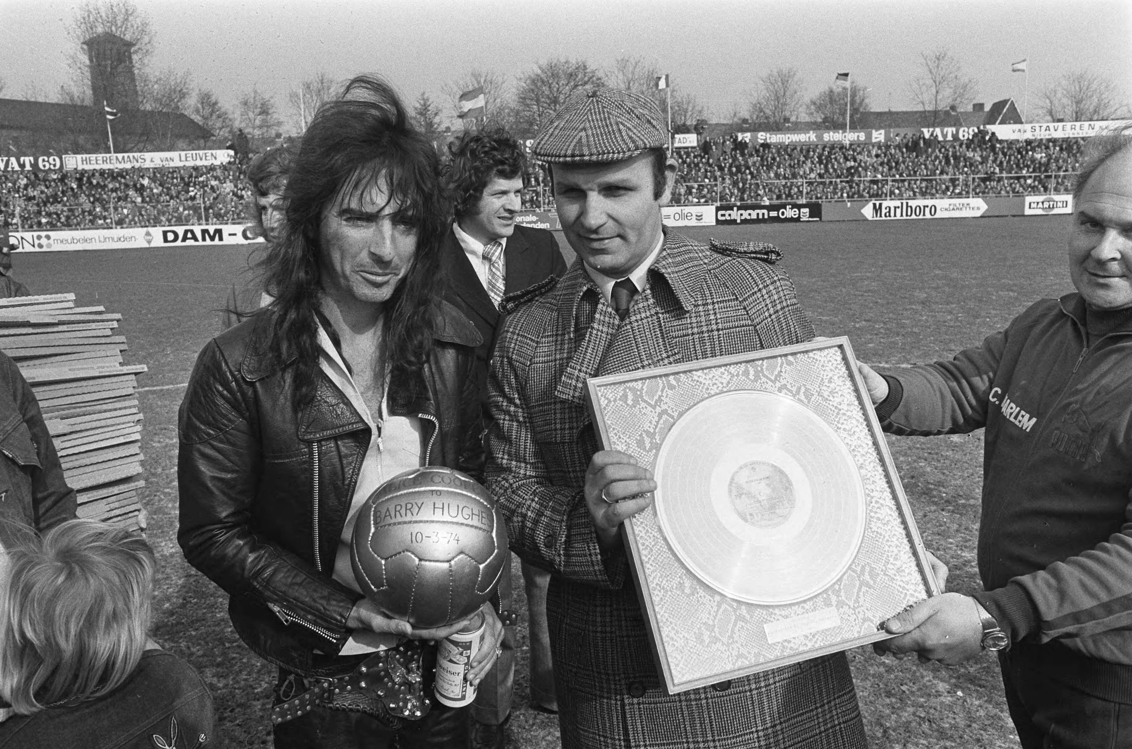 Haarlem tegen Ajax: 0-1 — Alice Cooper (l) en Barry Hughes met gouden bal en gouden plaat — Foto: Fotograaf Onbekend / Anefo. Licentie: Set B: Rechtenvrij / Publiek Domein. Bron: Nationaal Archief. http://hdl.handle.net/10648/ac457dec-d0b4-102d-bcf8-003048976d84