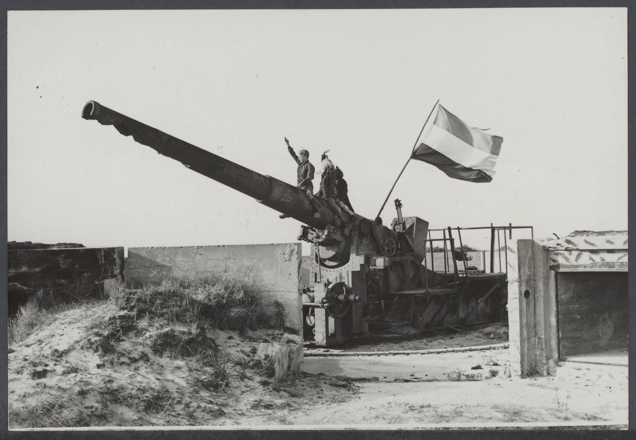 Slechten vestingwerken, vernietiging en vinden oorlogsmateriaal, demilitarisering, opslag, dumps. Nederland. — Westkapelle. De resten van de Westwal zijn een prachtige tribune, vanwaar de jeud een schitterend uitzicht heeft op de passerende stoet. Juichende kinderen op een kanon — Foto: Werff, Gé van der / ANP / Rechtenvrij. Licentie: Set B: Rechtenvrij / Publiek Domein. Bron: Nationaal Archief. http://hdl.handle.net/10648/c167abb3-a271-2767-6705-263848b8bbde