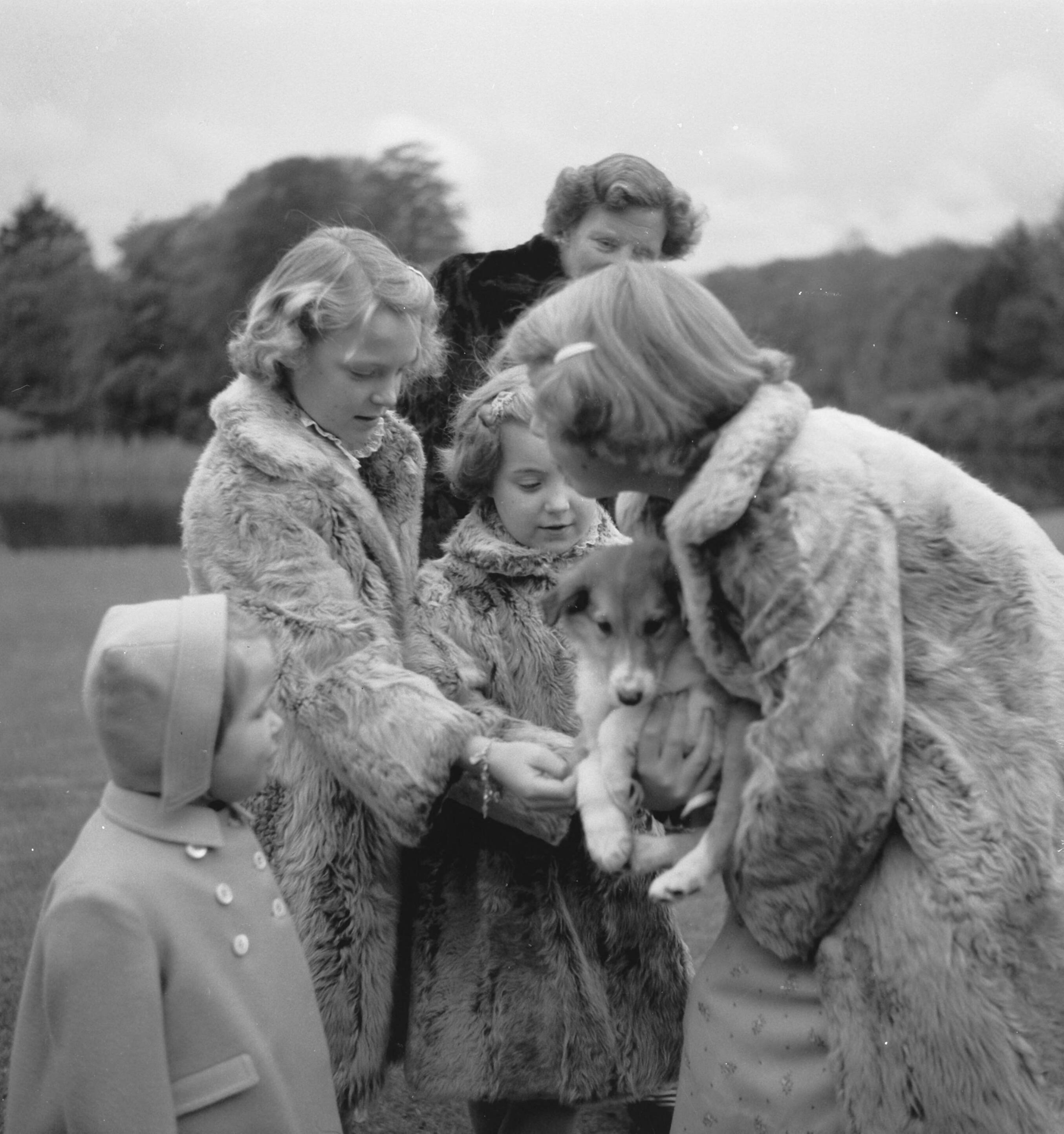 Reportage Koninklijk gezin op paleis Soestdijk — Koninklijk gezin op Soestdijk. Prinses Beatrix houdt een hondje vast. Bij haar staan prinses Margriet en prinses Marijke (Christina) en prinses Irene. Achter hen koningin Juliana — Foto: Noske, J.D. / Anefo. Licentie: Set B: Rechtenvrij / Publiek Domein. Bron: Nationaal Archief. http://hdl.handle.net/10648/a8e1b134-d0b4-102d-bcf8-003048976d84