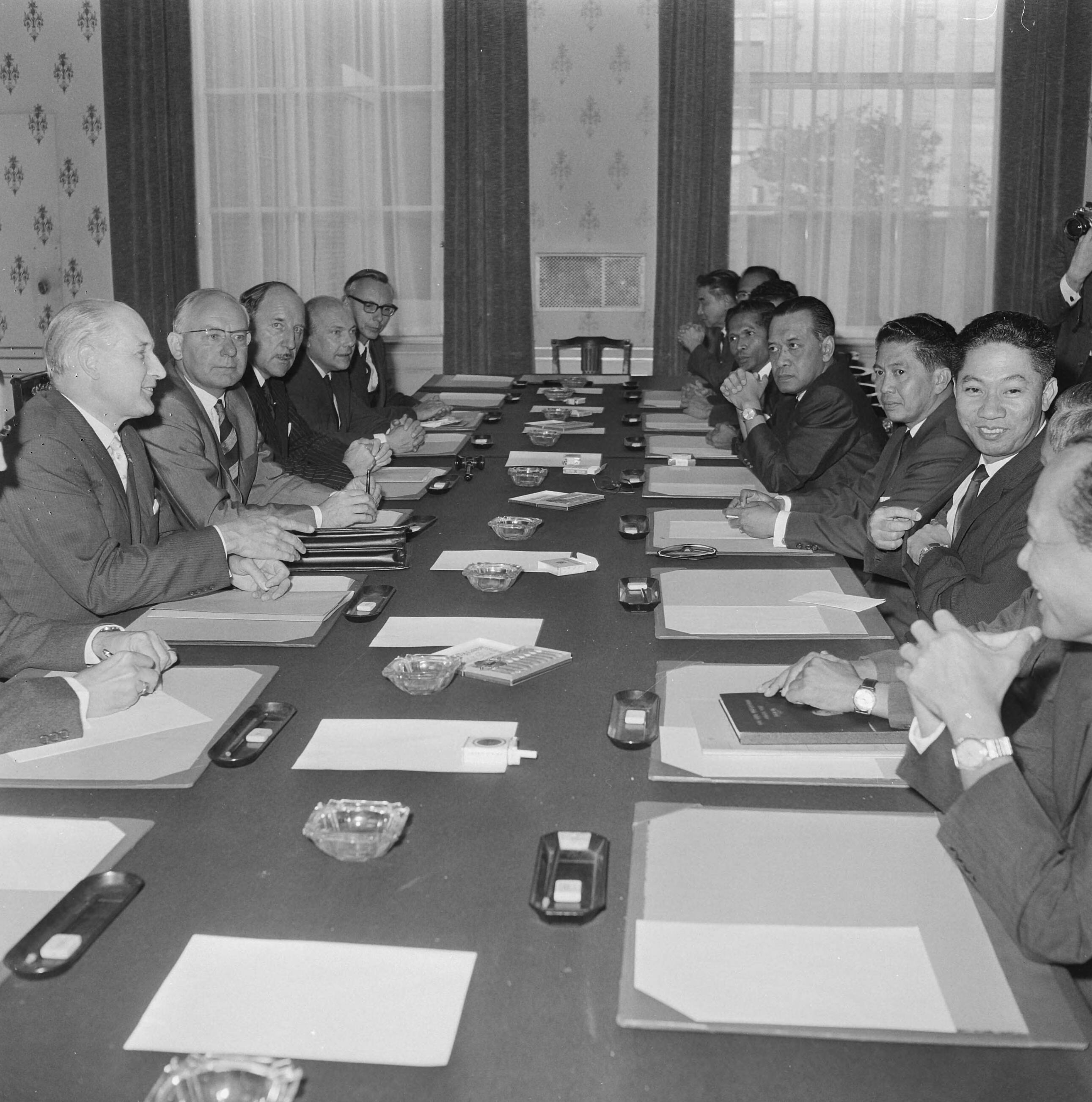 Nederland-Indonesië besprekingen te Den Haag — Deelnemers van de beprekingen aan de conferentietafel met ondermeer Minister A.Vondeling, Sultan Hamengkubuwana IX (minister van Economische Zaken van Indonesië), Minister J. Luns en Minister J. Den Uyl — Foto: Voets, Jan / Anefo. Licentie: Set B: Rechtenvrij / Publiek Domein. Bron: Nationaal Archief. http://hdl.handle.net/10648/aafb6b68-d0b4-102d-bcf8-003048976d84