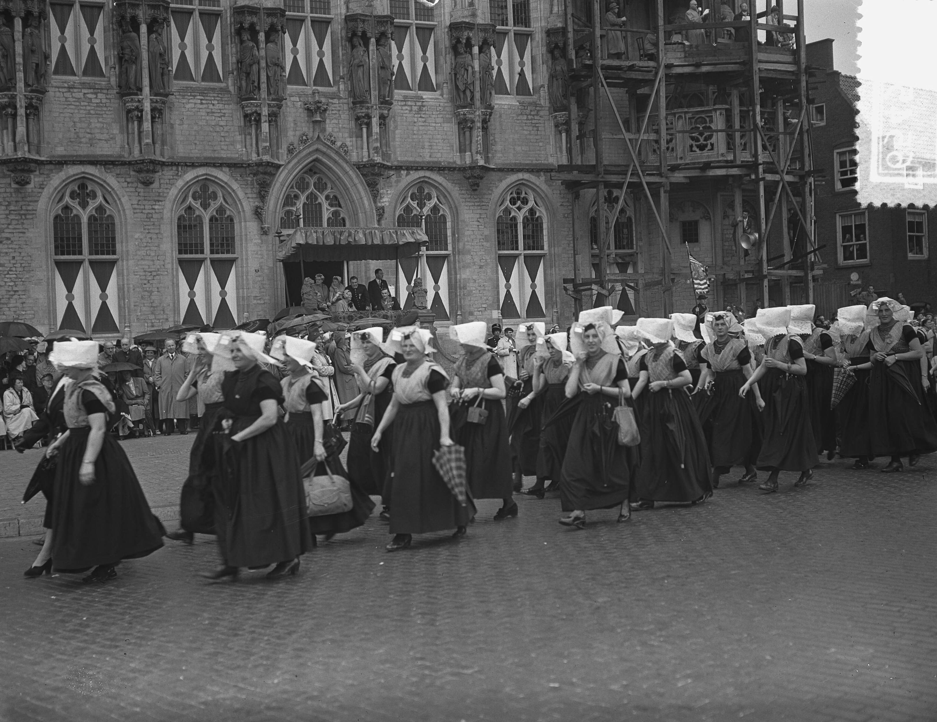 Koningin Juliana en prins Bernhard bezoeken Walcheren — Koningin Juliana en prins Bernhard bezoeken Middelburg, Défilé. Vrouwen in klederdracht voor het raadhuis — Foto: Bilsen, Joop van / Anefo. Licentie: Set B: Rechtenvrij / Publiek Domein. Bron: Nationaal Archief. http://hdl.handle.net/10648/a9245282-d0b4-102d-bcf8-003048976d84