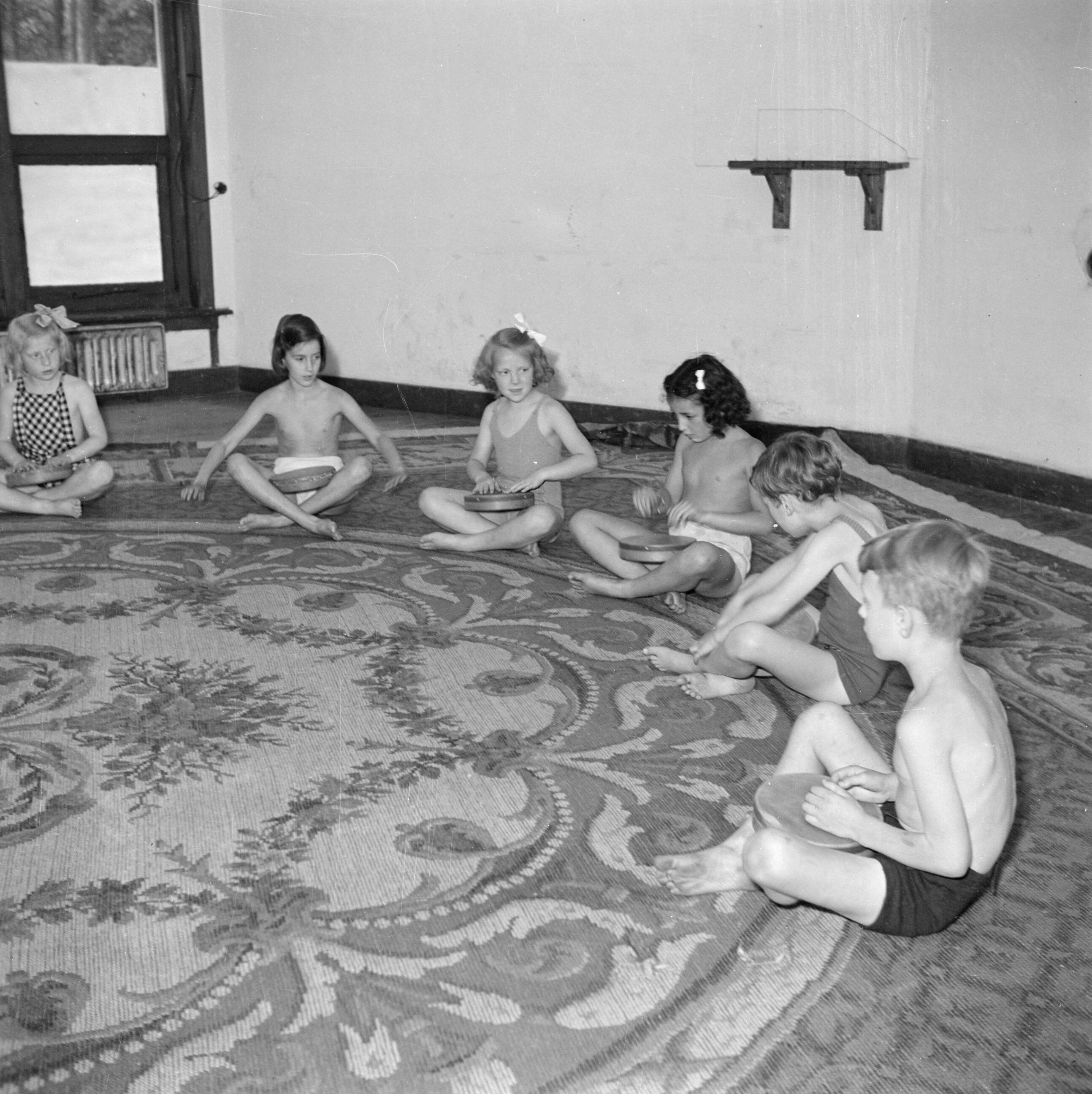 Prinses Beatrix en prinses Irene op de Werkplaats Kindergemeenschap van Kees Boeke te Bilthoven — Prinses Irene en klasgenoten maken muziek in gymkleding — Foto: Poll, Willem van de. Licentie: Set B: Rechtenvrij / Publiek Domein. Bron: Nationaal Archief. http://hdl.handle.net/10648/aee817a8-d0b4-102d-bcf8-003048976d84