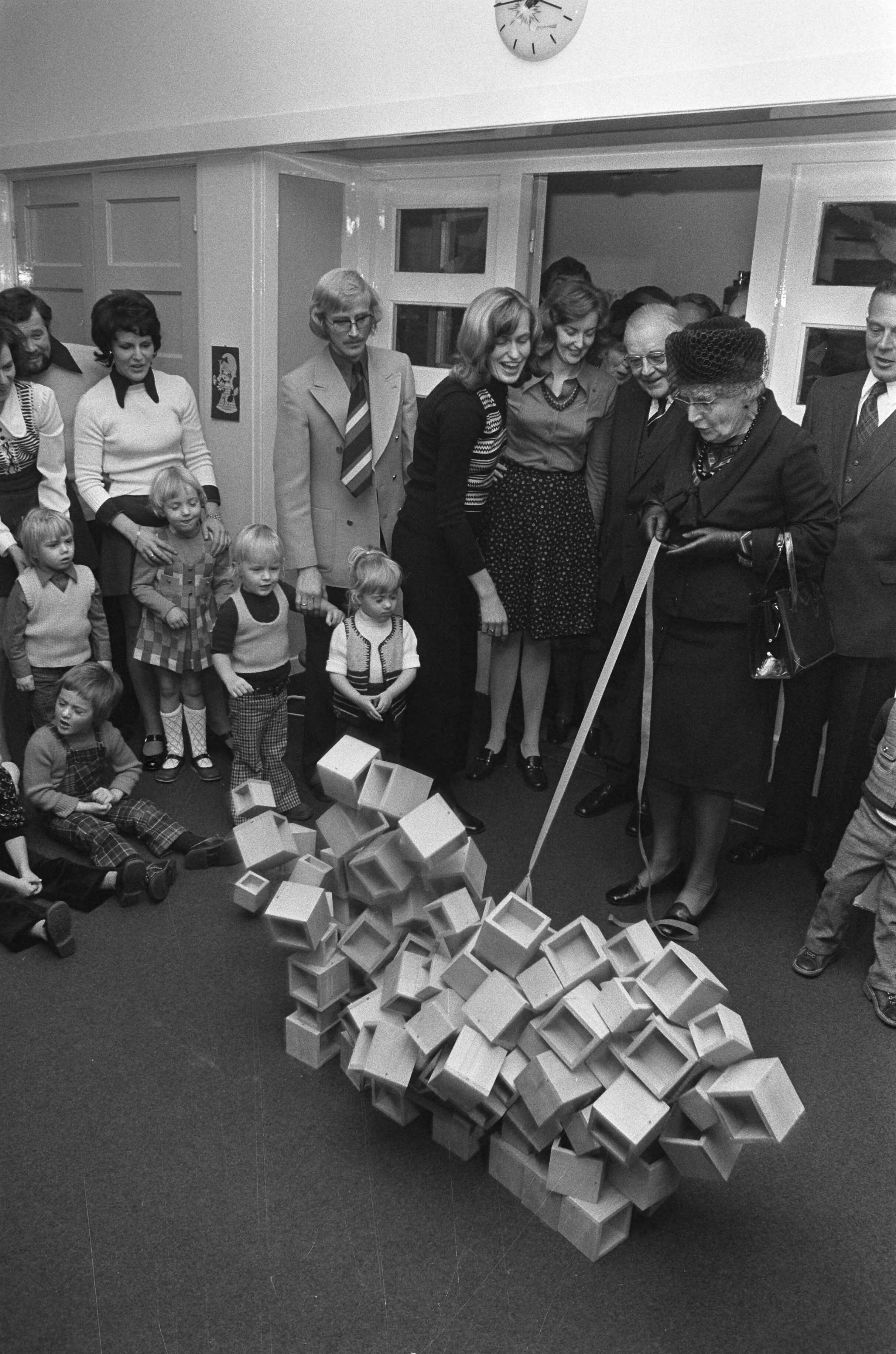 Koningin Juliana bezoekt scholen in Den Haag — De koningin bekijkt een project van de kinderen in een peuterspeelzaal — Foto: Fotograaf Onbekend / Anefo. Licentie: Set B: Rechtenvrij / Publiek Domein. Bron: Nationaal Archief. http://hdl.handle.net/10648/ac3c3ebc-d0b4-102d-bcf8-003048976d84