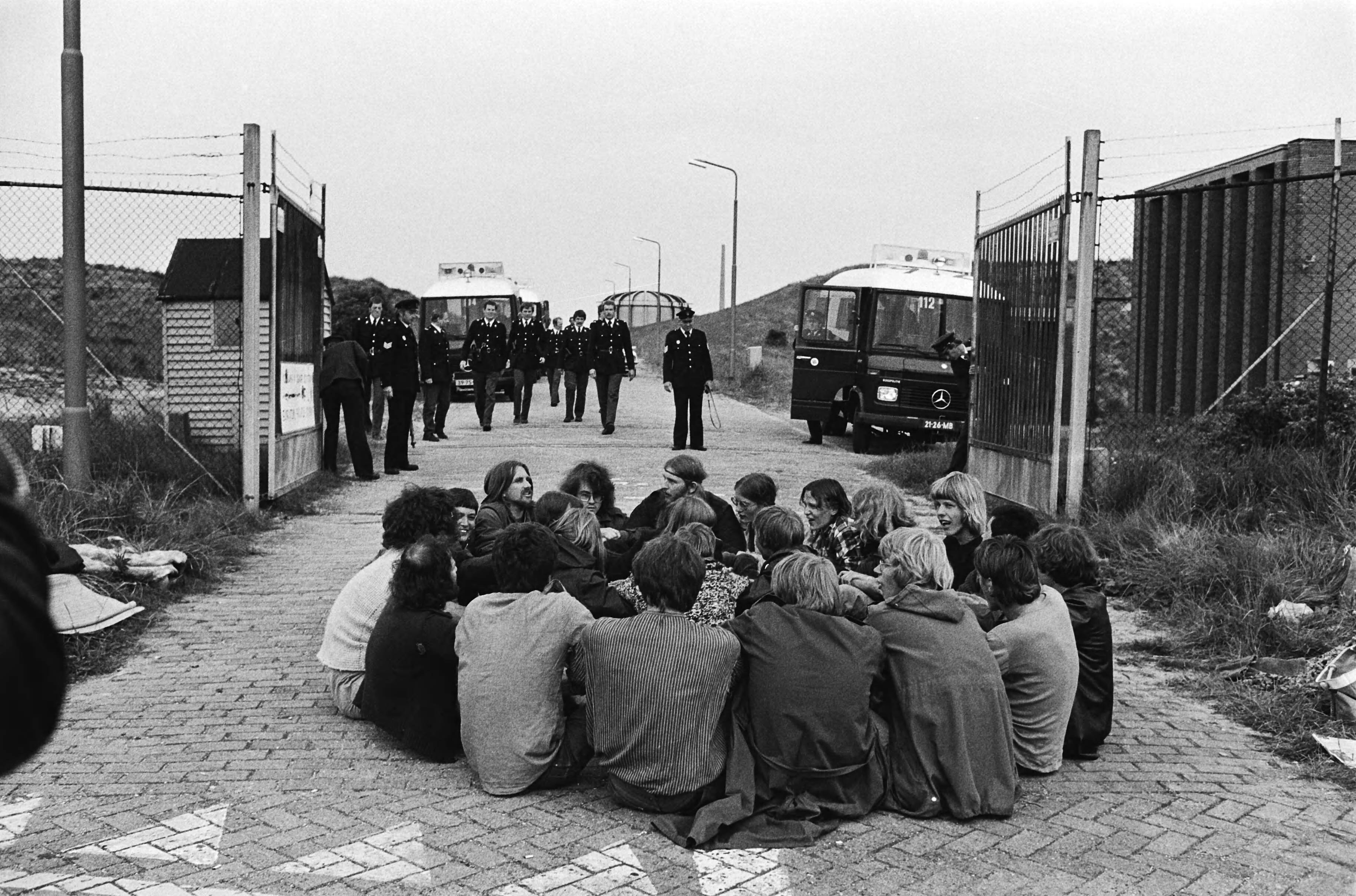 Aktiegroep blokkeert de uitgang van Reactorcentrum Petten uit protest tegen de dumping van afval in zee — Demonstranten voor de uitgang — Foto: Suyk, Koen / Anefo. Licentie: Set B: Rechtenvrij / Publiek Domein. Bron: Nationaal Archief. http://hdl.handle.net/10648/accc21a8-d0b4-102d-bcf8-003048976d84