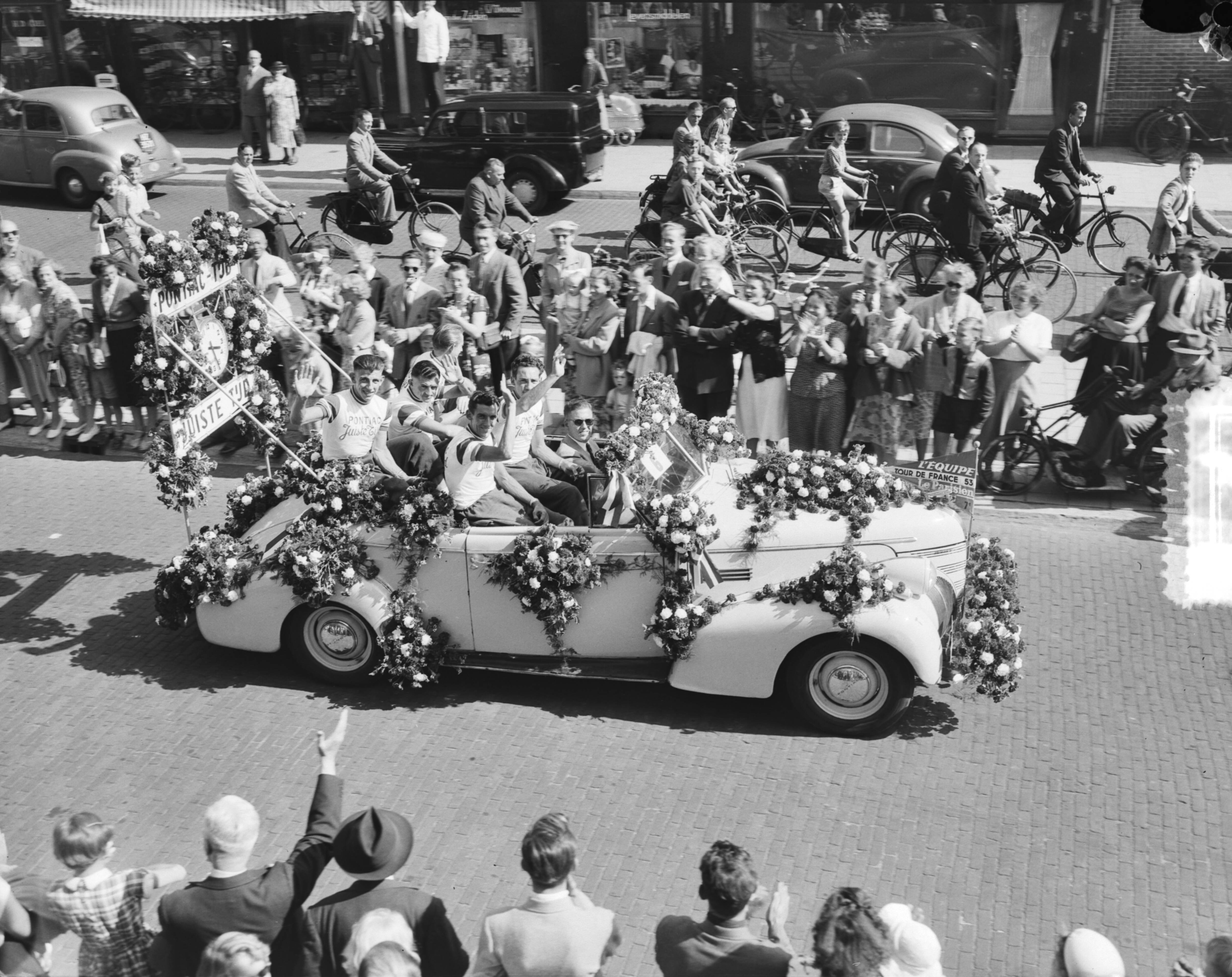 Bloemencorso in Den Haag 1953 — Bloemencorso in Den Haag. Tour de France ploeg in wagen — Foto: Duinen, G.W. van / Anefo. Licentie: Set B: Rechtenvrij / Publiek Domein. Bron: Nationaal Archief. http://hdl.handle.net/10648/a910bd30-d0b4-102d-bcf8-003048976d84