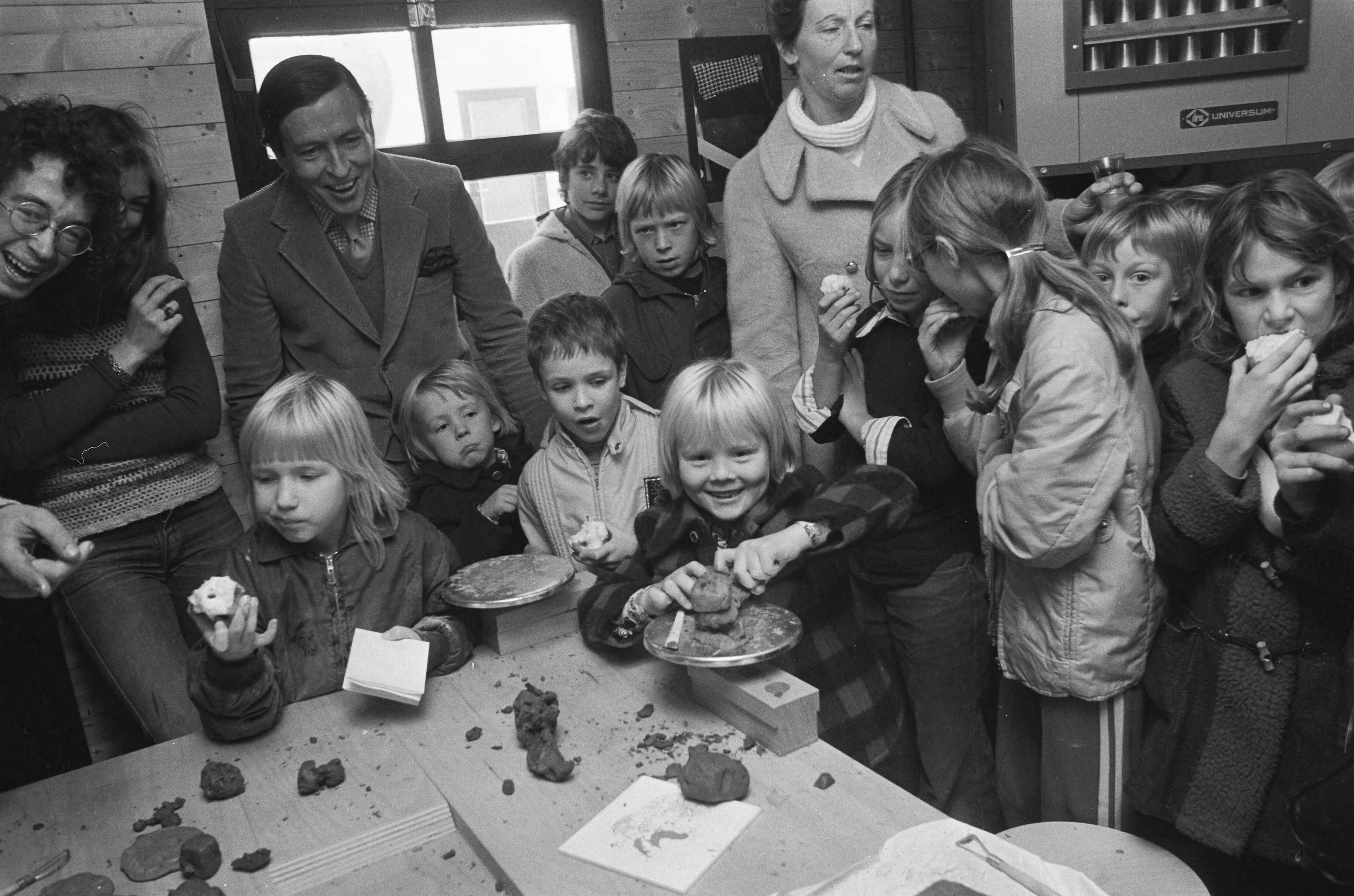 Prinses Beatrix en Prins Claus met hun kinderen bij de opening van kinderboerderij "De Vrije Teugel" in Soest — Prins Willem-Alexander (rechts aan tafel) boetseert, op de achtergrond Prins Claus — Foto: Fotograaf Onbekend / Anefo. Licentie: Set B: Rechtenvrij / Publiek Domein. Bron: Nationaal Archief. http://hdl.handle.net/10648/ac3ca6cc-d0b4-102d-bcf8-003048976d84