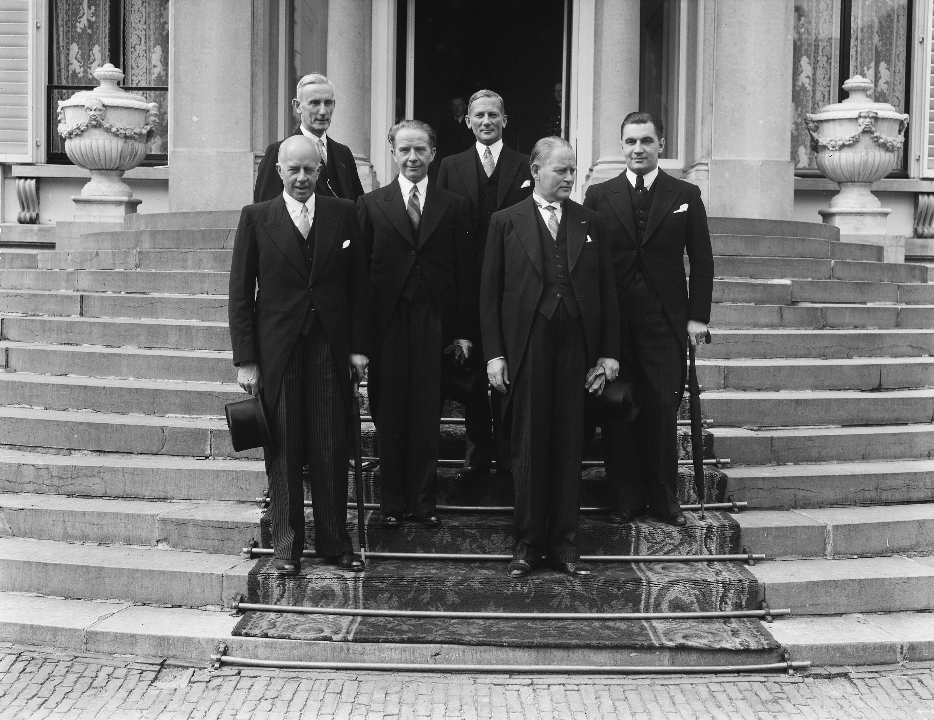 Fotocollectie Anefo — De Prinses-Regentes, Prinses Juliana, heeft ten Paleize Soestdijk de nieuwe ministers beëdigd. Na afloop poseerden de ministers met uitzondering van de heer Van Schaik, die nog enige tijd in het Paleis verbleef, op het bordes. Van rechts naar links: Mr. E. M. J. A. Sassen, Mr. D. U. Stikker, Mr. W. F. Schokking, Prof. dr. F. J. Th. Rutten, Mr. Th. R. J. Wijers en Mr. A. M. Joekes. — Foto: Merk, Ben / Anefo. Licentie: Set B: Rechtenvrij / Publiek Domein. Bron: Nationaal Archief. http://hdl.handle.net/10648/a8bae874-d0b4-102d-bcf8-003048976d84