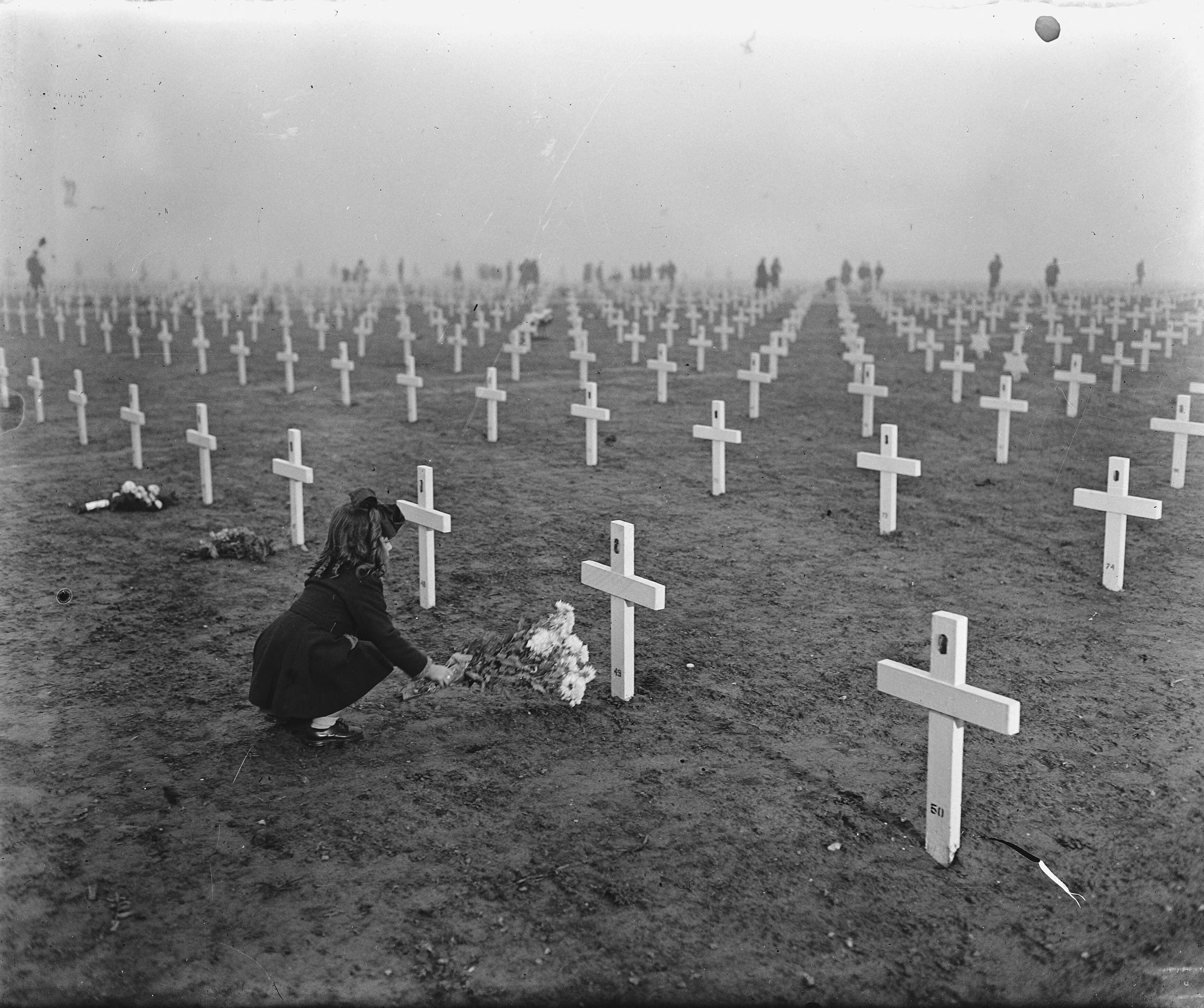 Amerikaanse militaire begraafplaats te Margraten — Klein meisje legt bloemen bij een graf — Foto: Raucamp, Koos / Anefo. Licentie: Set B: Rechtenvrij / Publiek Domein. Bron: Nationaal Archief. http://hdl.handle.net/10648/ac052aee-d0b4-102d-bcf8-003048976d84