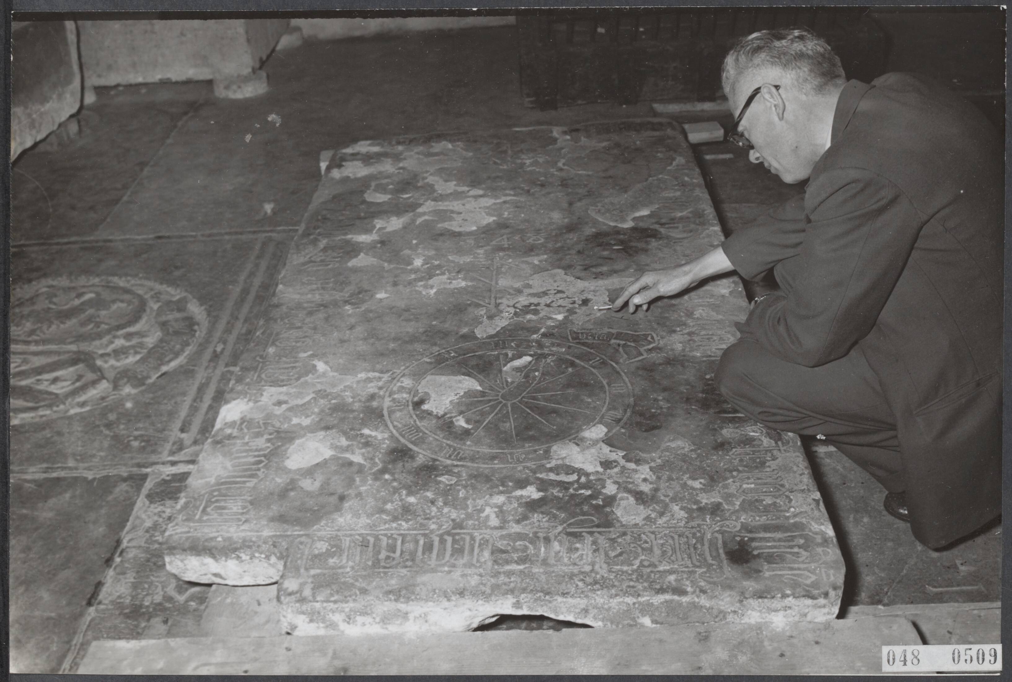 Fotocollectie Elsevier Binnenland — In de St. Bavokerk te Haarlem heeft men een grafsteen ontdekt, waarvan men aanneemt dat het de oudste uit deze kerk is. Hij is van Jan Woutsen (gestorven op 1 februari 1518) en daar op de steen een afbeelding van een klok voorkomt gelij aan die welke boven in het schip van de St. Bavo hangt is het vermoeden gewettigd, dat men het graf van de maker van deze klok te doen heeft en hij dus klokkemaker van beroep was — Foto: Fotograaf Onbekend / Anefo. Licentie: Set B: Rechtenvrij / Publiek Domein. Bron: Nationaal Archief. http://hdl.handle.net/10648/ae01426a-d0b4-102d-bcf8-003048976d84