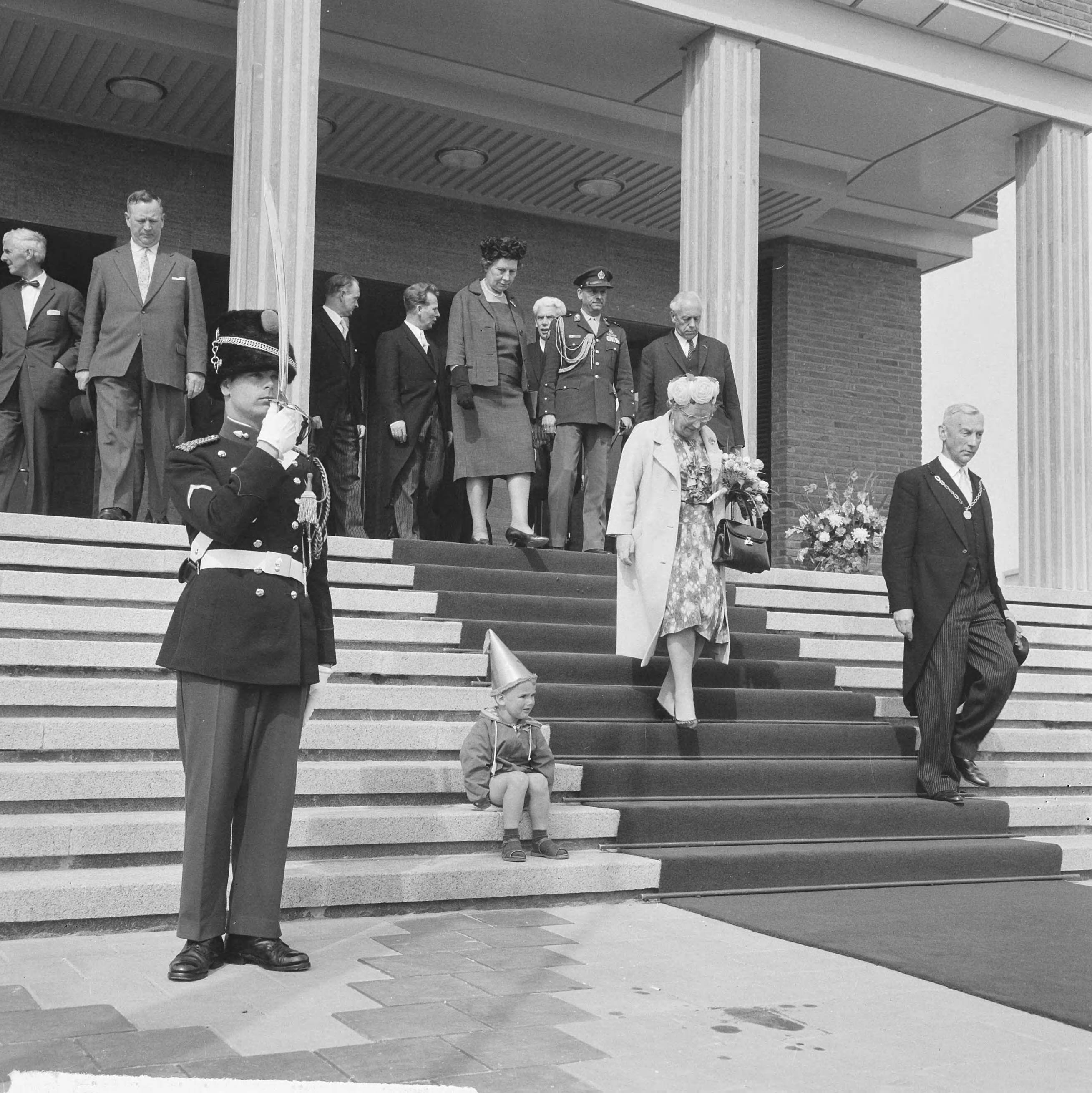 Koningin Juliana opent het nieuwe stadhuis te Vlissingen — Een klein jochie met feestmuts zit op de trappen van het stadhuis, terwijl konining Juliana de trap afdaalt — Foto: Nijs, Jac. de / Anefo. Licentie: Set B: Rechtenvrij / Publiek Domein. Bron: Nationaal Archief. http://hdl.handle.net/10648/ace4bef6-03c7-f3ae-7fe9-f000e6def7b4