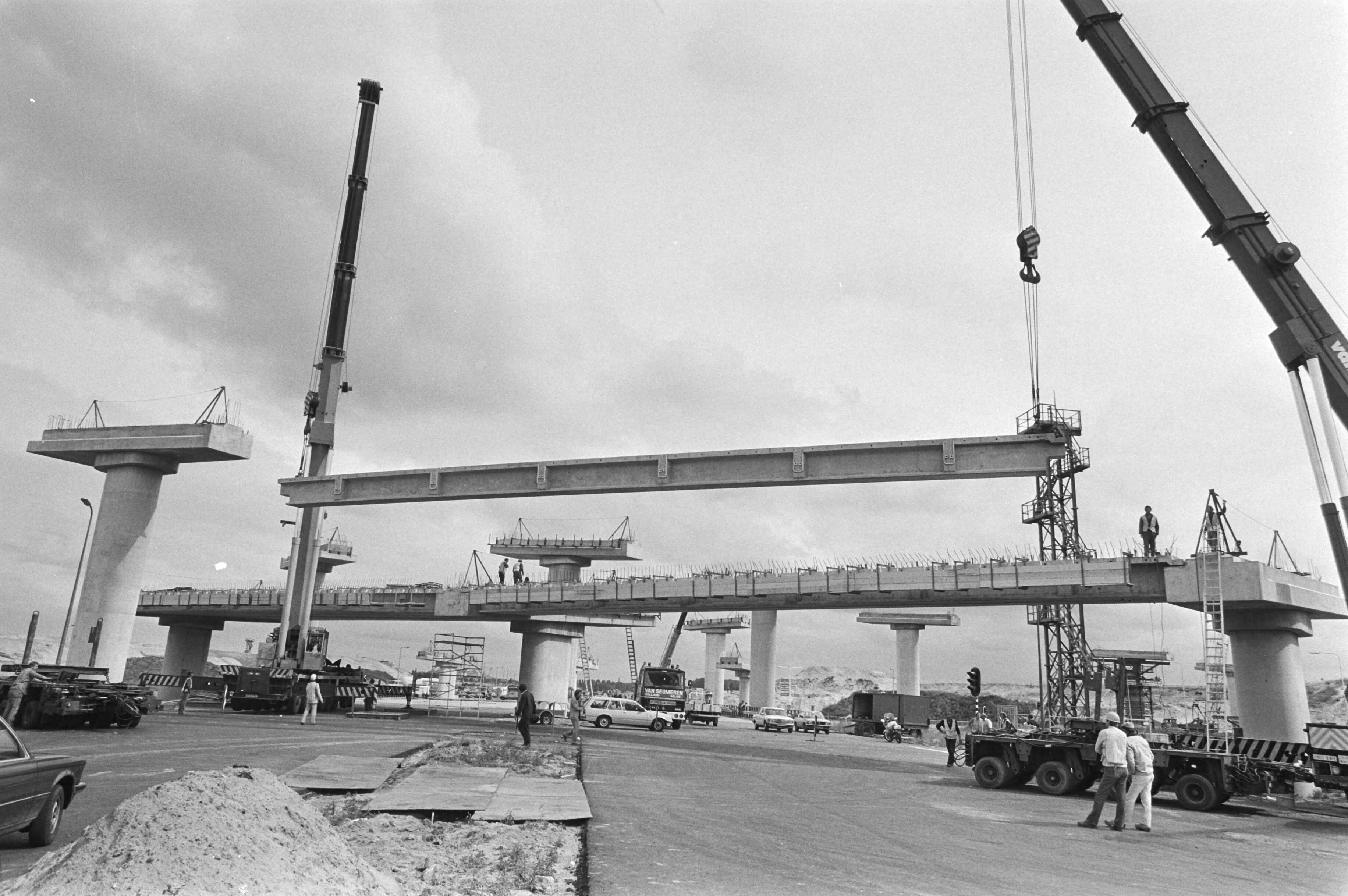 Vijfendertig meter lange betonbalken worden geplaatst verkeersplein Leidschendam (kruising A4 en A12). — Het plaatsen van dwarsliggers op de oplegtafels — Foto: Croes, Rob C. / Anefo. Licentie: Set B: Rechtenvrij / Publiek Domein. Bron: Nationaal Archief. http://hdl.handle.net/10648/ad01f2ba-d0b4-102d-bcf8-003048976d84