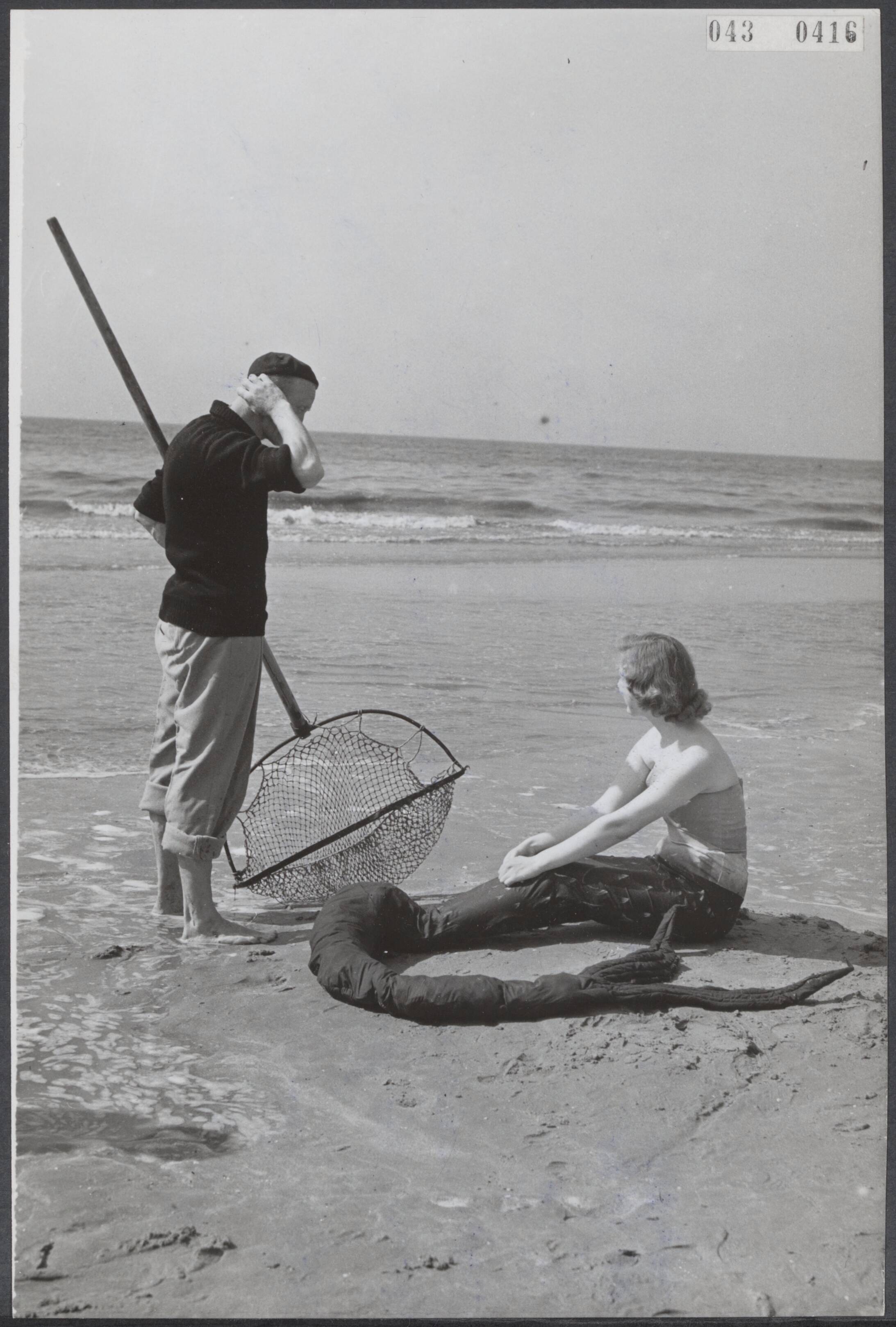 Fotocollectie Elsevier Binnenland — Opening van het badseizoen van Zandvoort. Een garnalenvisser staat bij een "zeemeermin" — Foto: Fotograaf Onbekend / Anefo. Licentie: Set B: Rechtenvrij / Publiek Domein. Bron: Nationaal Archief. http://hdl.handle.net/10648/adf8ecd2-d0b4-102d-bcf8-003048976d84