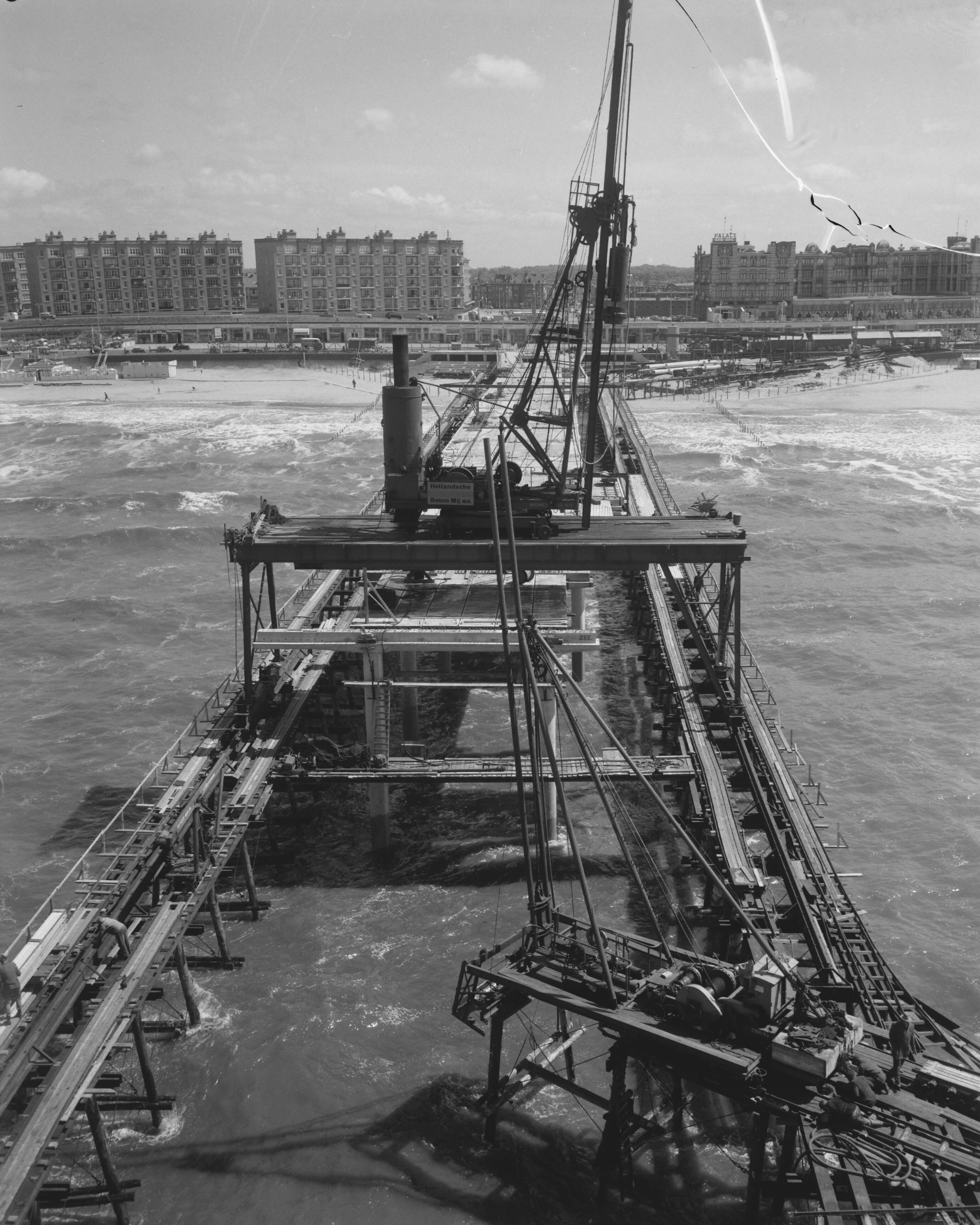 Fotocollectie Anefo — Bouw pier te Scheveningen, overzicht van de pier naar het strand — Foto: Behrens, Herbert F. / Anefo. Licentie: Set B: Rechtenvrij / Publiek Domein. Bron: Nationaal Archief. http://hdl.handle.net/10648/a9afe040-d0b4-102d-bcf8-003048976d84