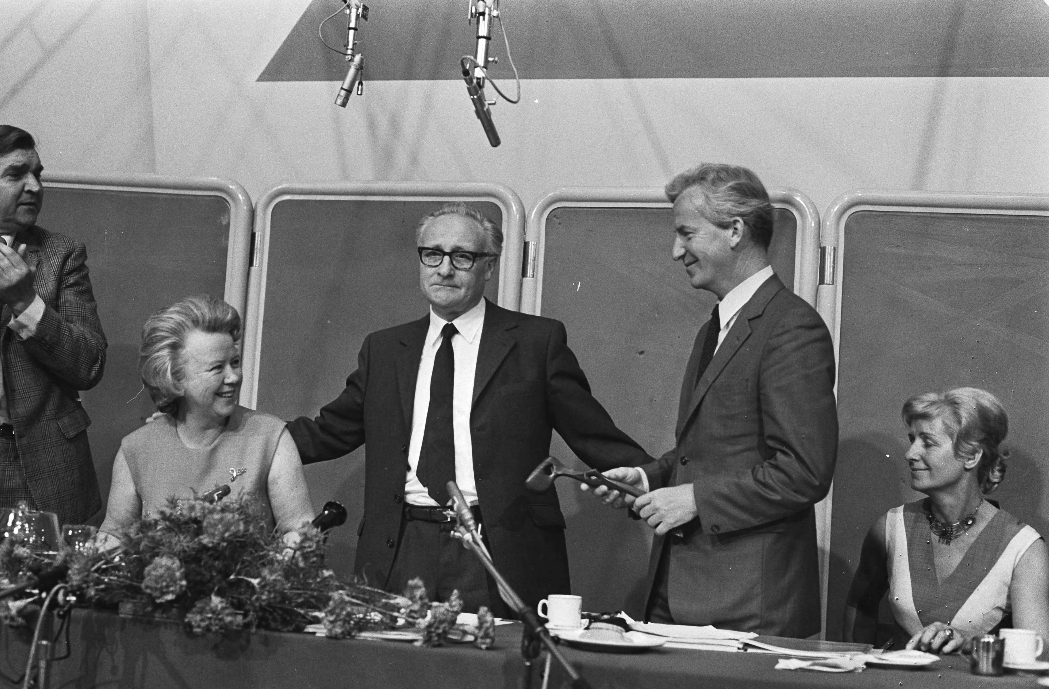 André Kloos volgt Jan Broeksz op als voorzitter van de VARA te Hilversum — V.l.n.r. mevrouw Broeksz, Jan Broeksz en André Kloos met de voorzittershamer — Foto: Fotograaf Onbekend / Anefo. Licentie: Set B: Rechtenvrij / Publiek Domein. Bron: Nationaal Archief. http://hdl.handle.net/10648/abbe5c86-d0b4-102d-bcf8-003048976d84