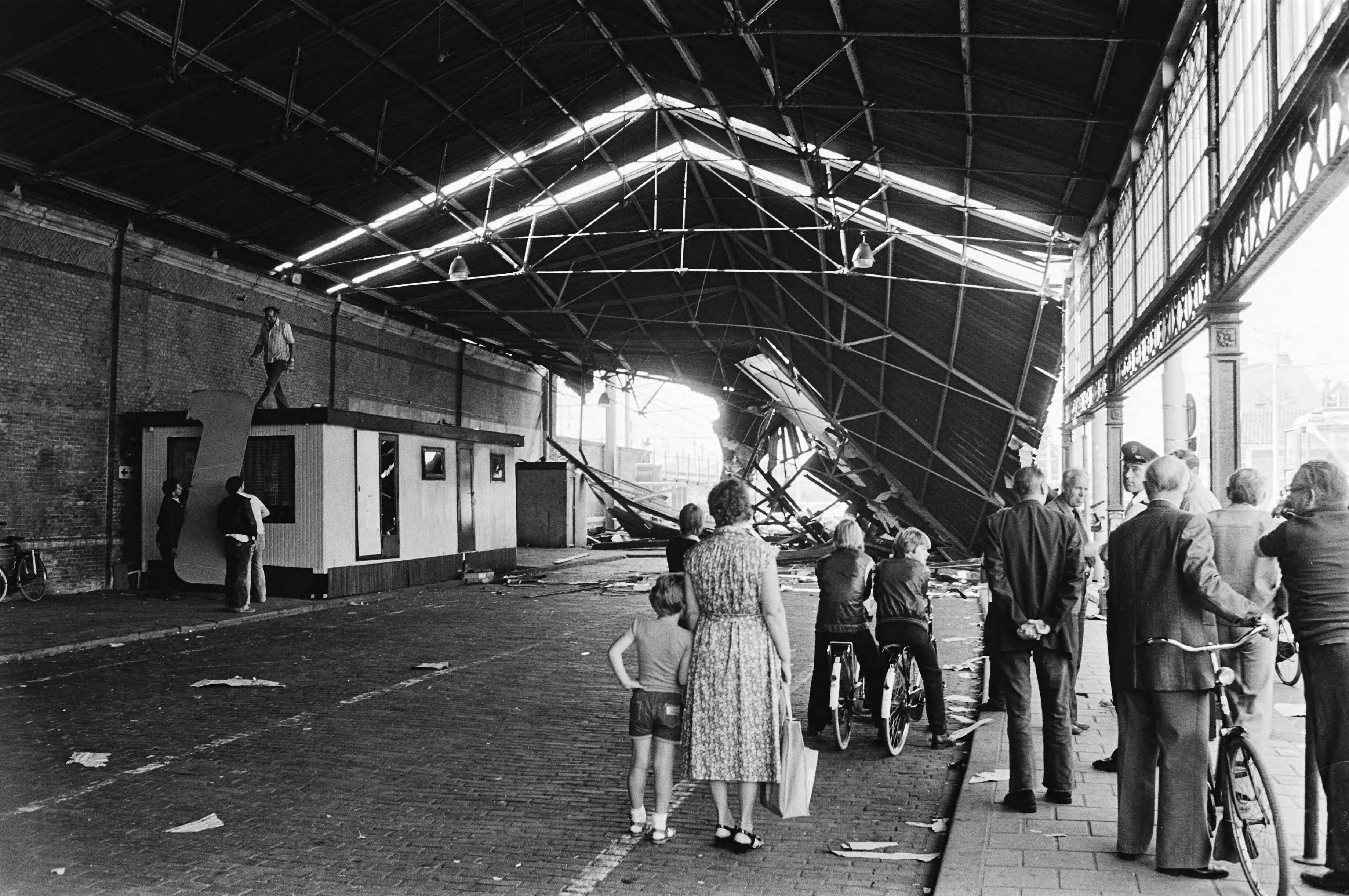 Ingestort gedeelte van de dakconstructie van station Hollands Spoor in Den Haag na de aanrijding door een vrachtauto — Den Haag|Zuid-Holland|stations |instortingen |publiek|Hollands Spoor — Foto: Suyk, Koen / Anefo. Licentie: Set B: Rechtenvrij / Publiek Domein. Bron: Nationaal Archief. http://hdl.handle.net/10648/accf3c30-d0b4-102d-bcf8-003048976d84